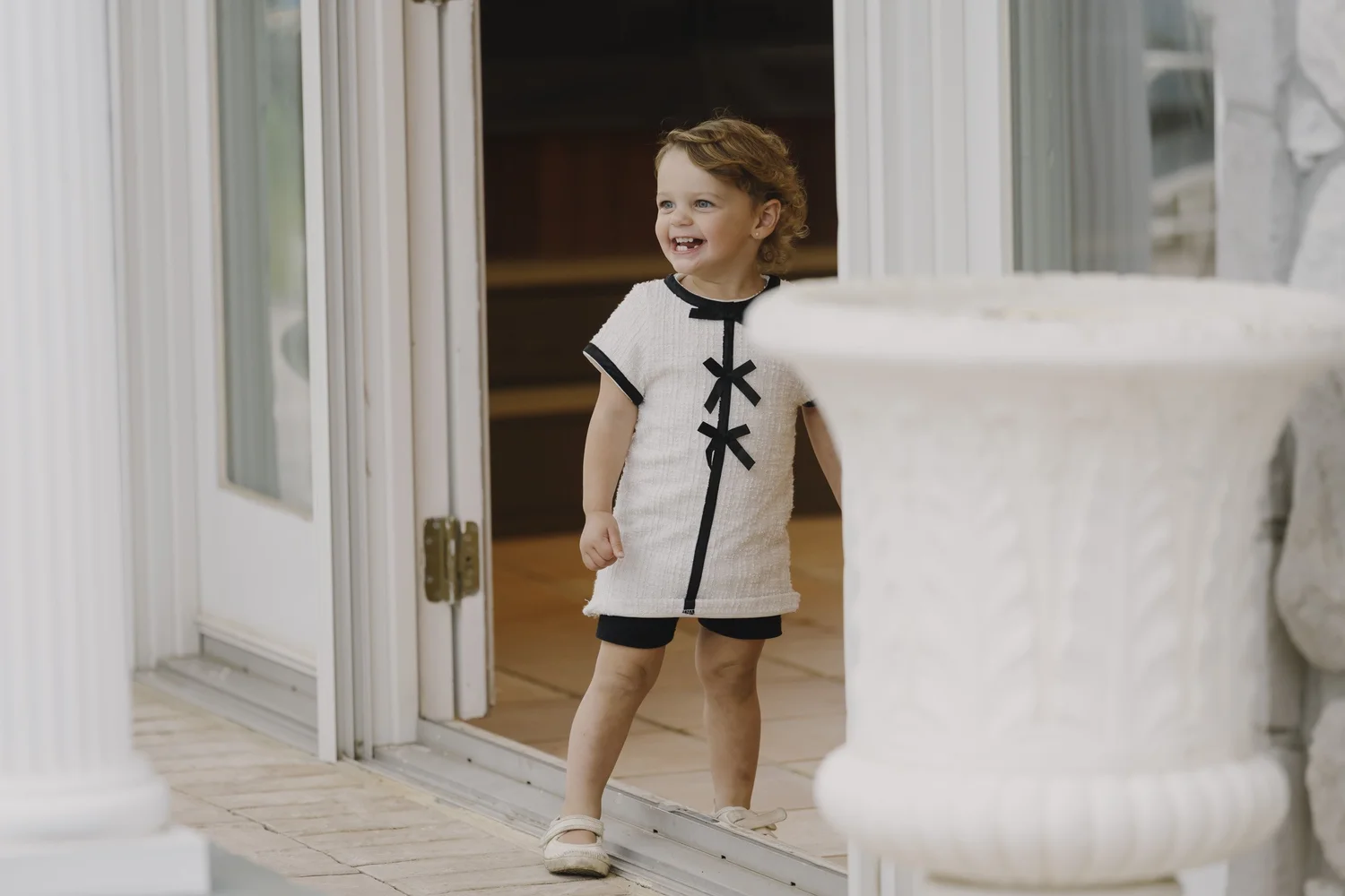 A smiling young child standing in the doorway during the home celebration