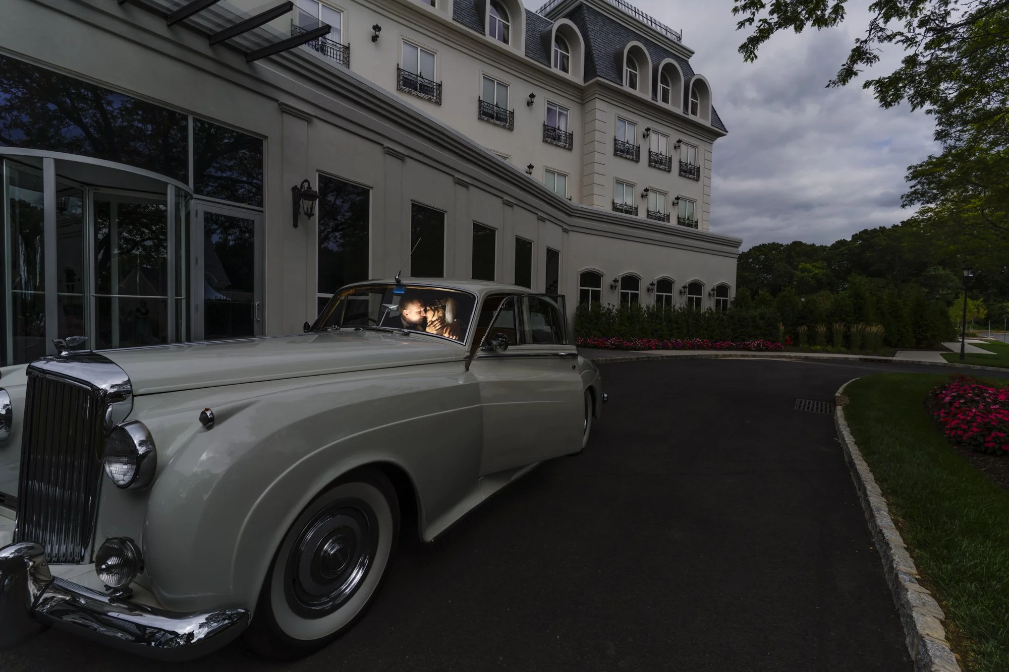 Wedding couple in a vintage white car outside Château Grande Hotel
