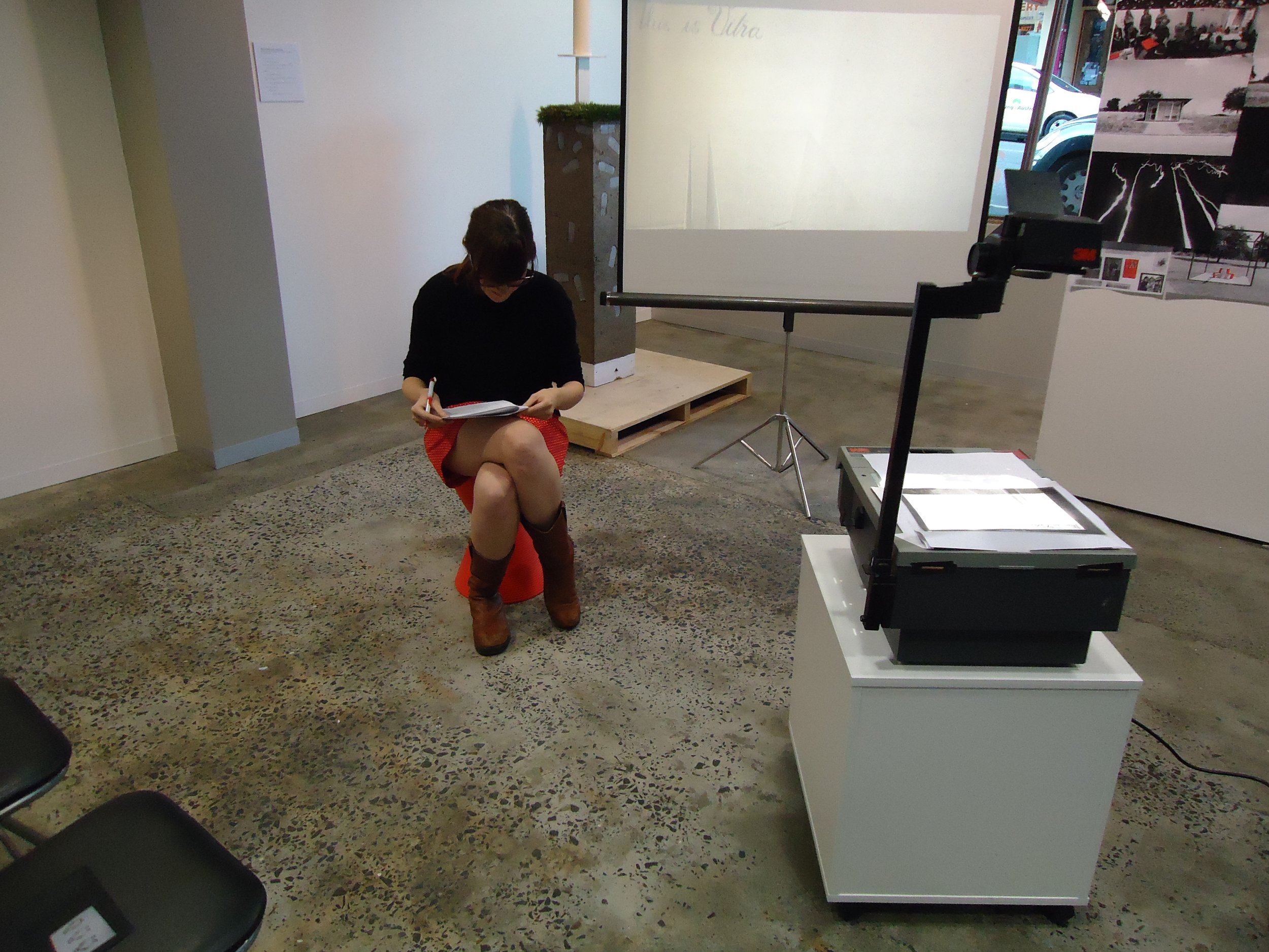  A seated woman in black long sleeves and red skirt browsing through the papers on her hands. 