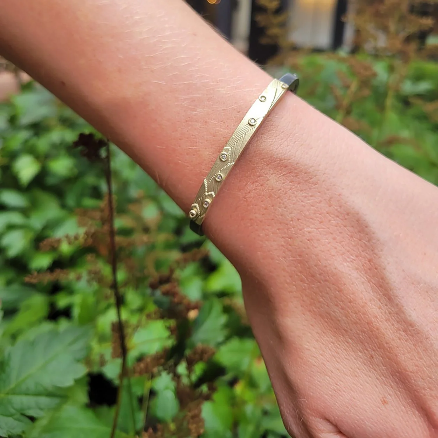 Feather & Tube Set Diamond Hinged Bracelet, Gold and Silver. Worn by white female model. Handmade fine art jewelry by Rebecca Myers Design.