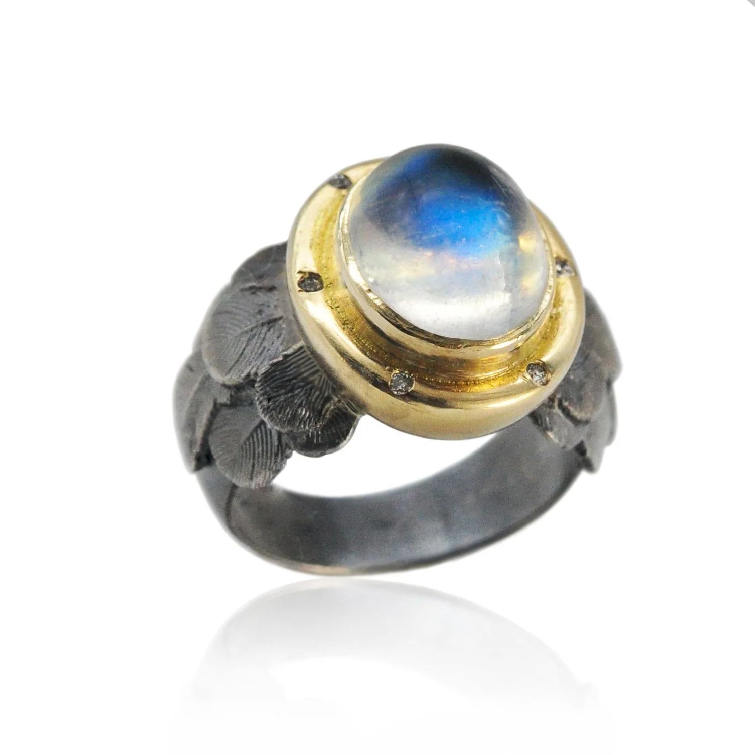 Feather Halo Ring with Moonstone Cabochon. Oval moonstone cabochon, 14k yellow gold, oxidized silver, flush set white diamonds. Handmade fine art jewelry by Rebecca Myers Design.