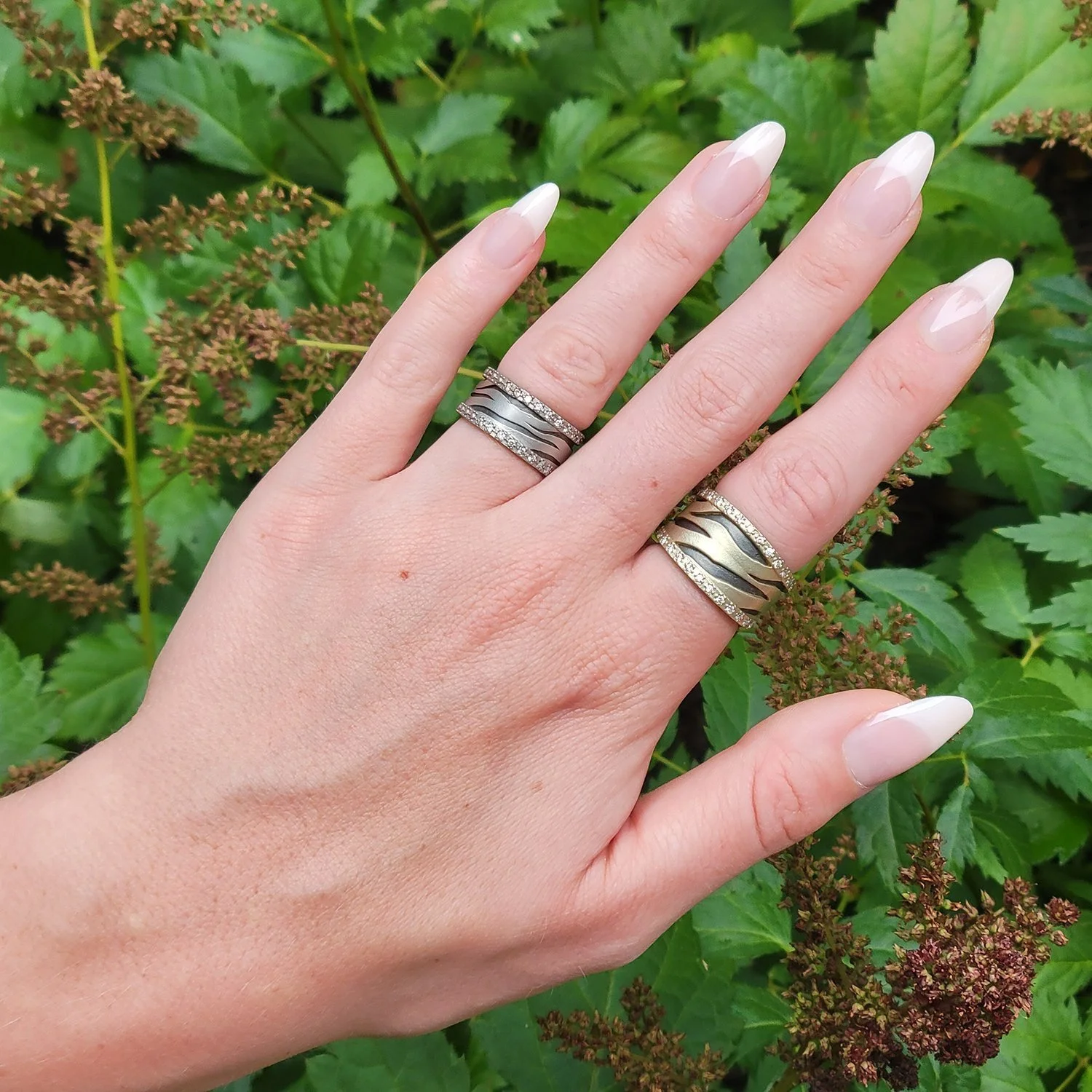 Tiger & Zebra Stripe Rings. 14k yellow gold, 14k white gold, oxidized silver, pave set diamonds. On white femaie model. Handmade fine art jewelry by Rebecca Myers Design.
