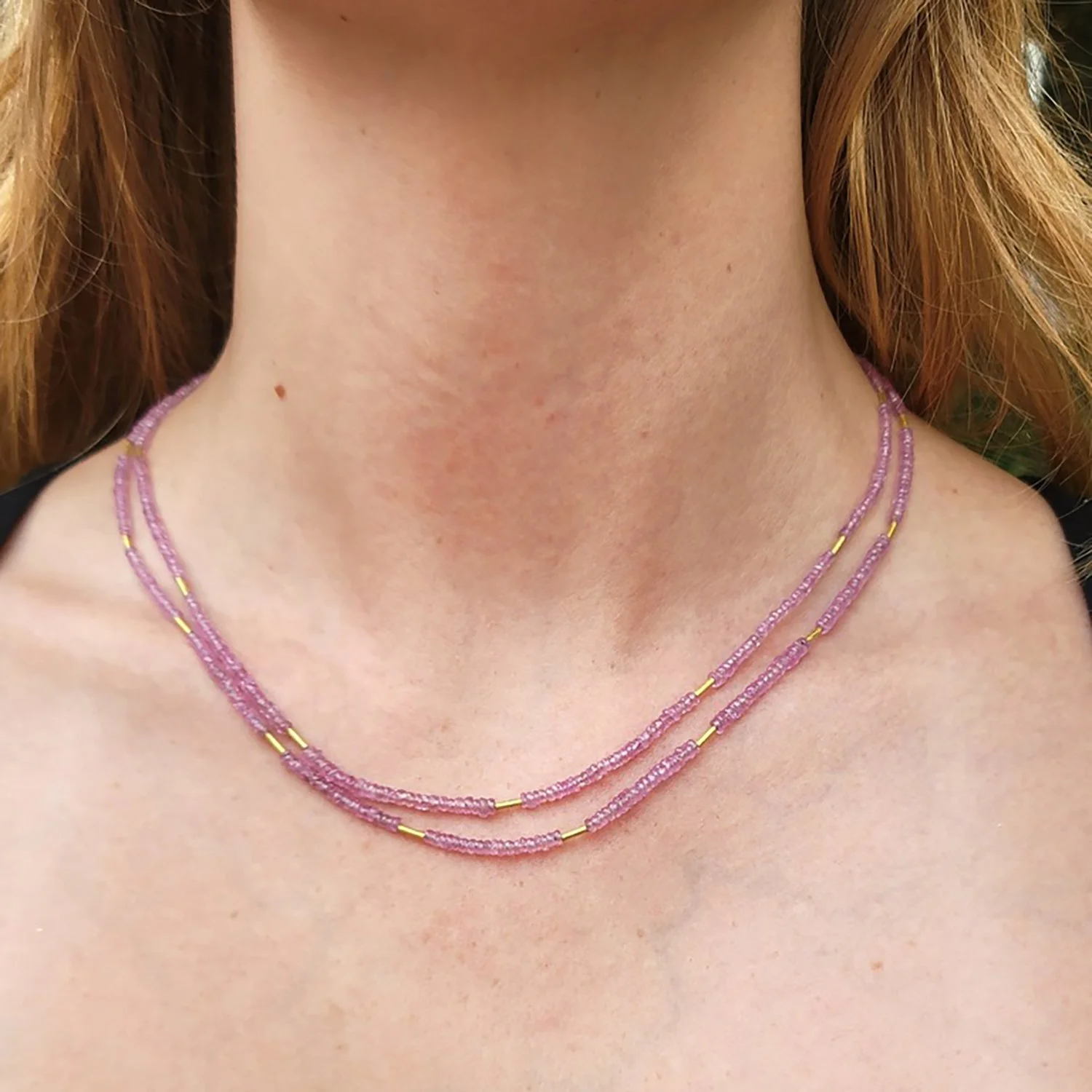 Faceted Pink Sapphire Beaded Necklaces. Faceted pink sapphire beads, 20k yellow gold beads, 14k yellow gold clasp. Shown on white female model. Handmade fine art jewelry by Rebecca Myers Design.