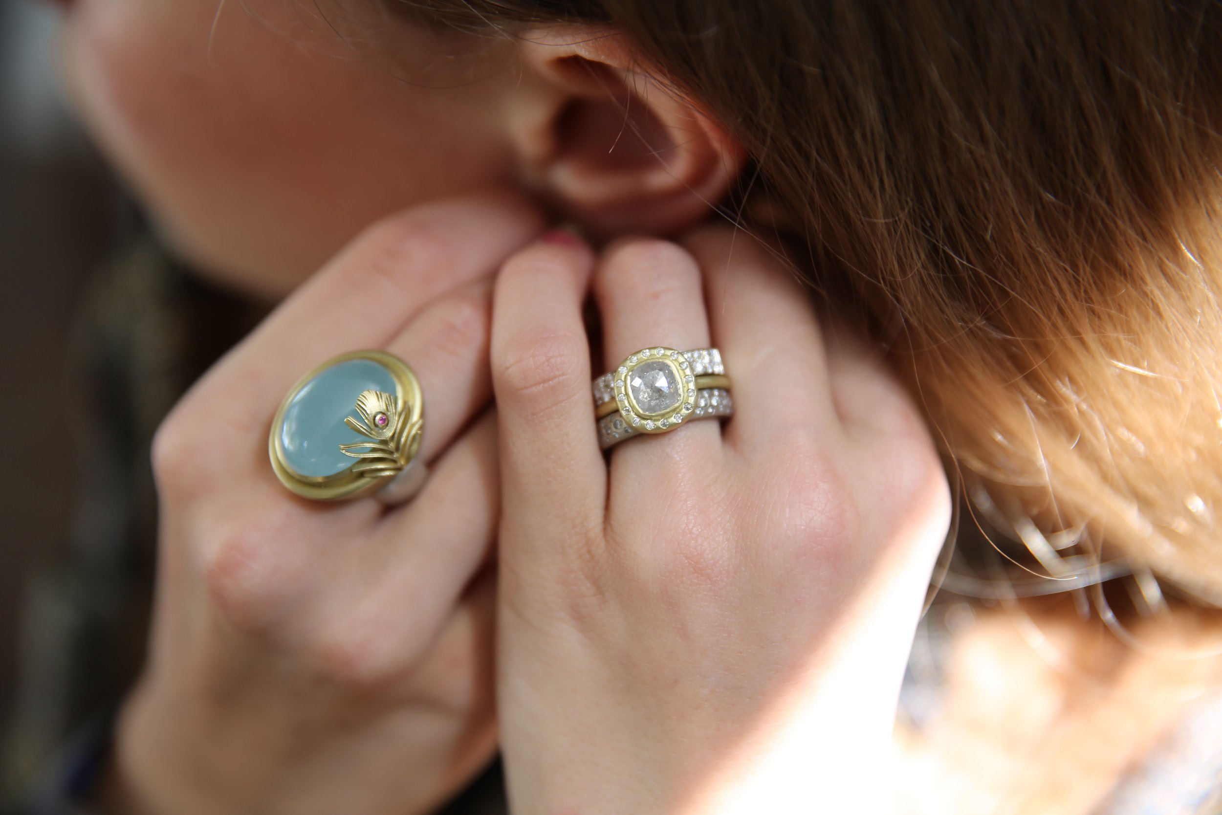 Cushion cut light grey diamond halo ring modeled on white woman. Handmade fine art jewelry by Rebecca Myers Design.