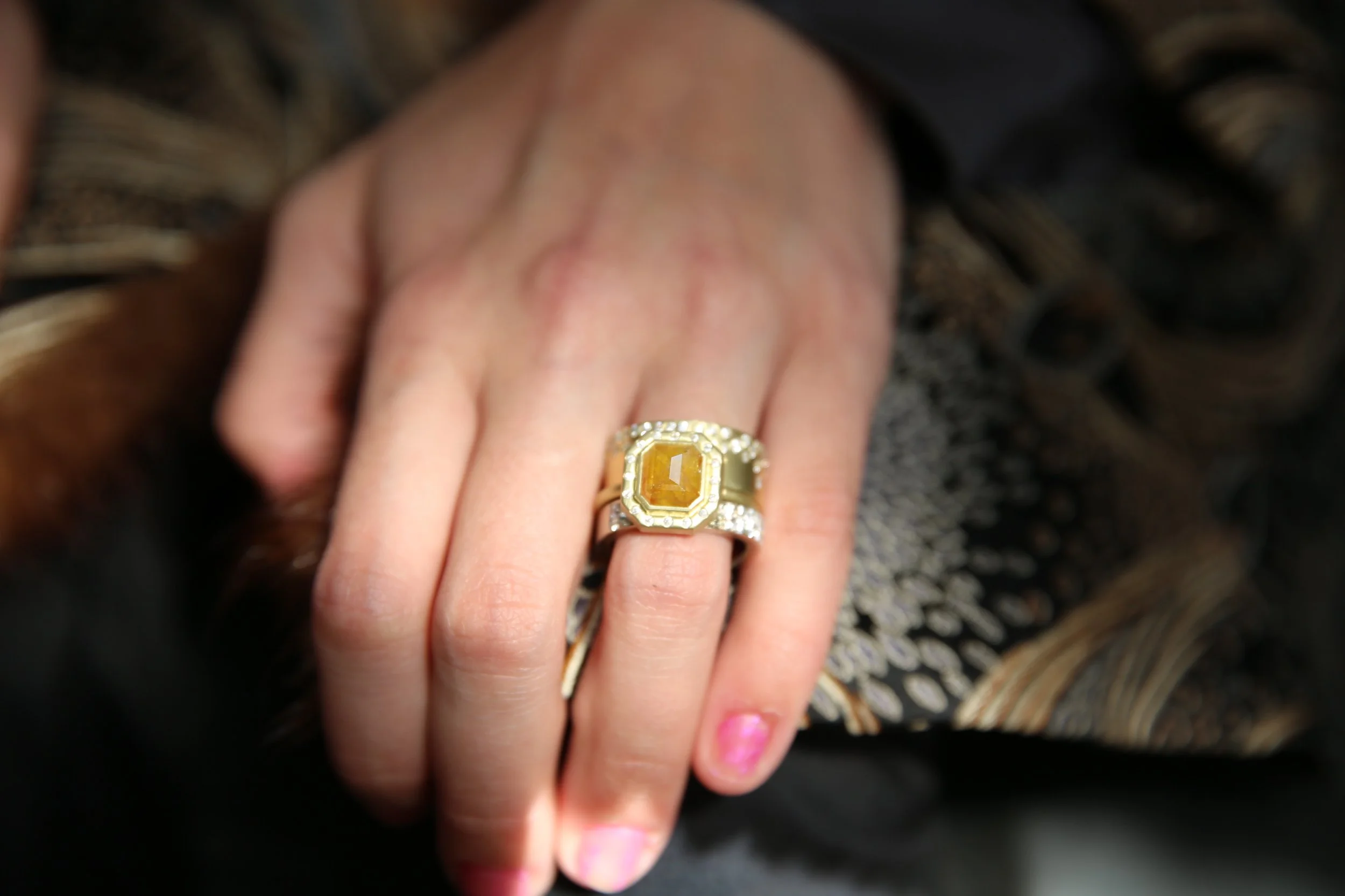 Emerald cut brown diamond halo ring modeled on white woman. Handmade fine art jewelry by Rebecca Myers Design.
