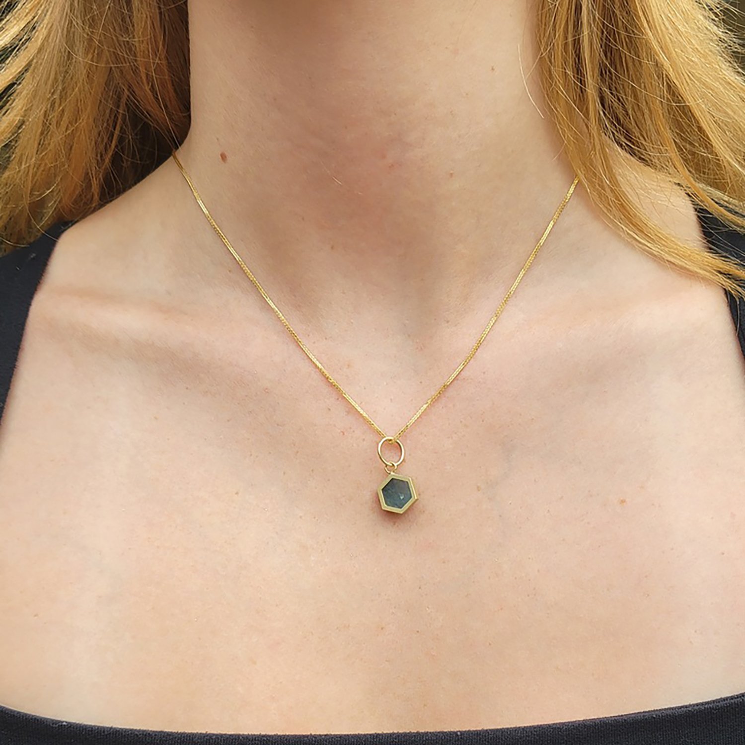 Hexagonal Aquamarine Slice Charm. 14k yellow gold, aquamarine slice. On white female model. Handmade fine art jewelry by Rebecca Myers Design.