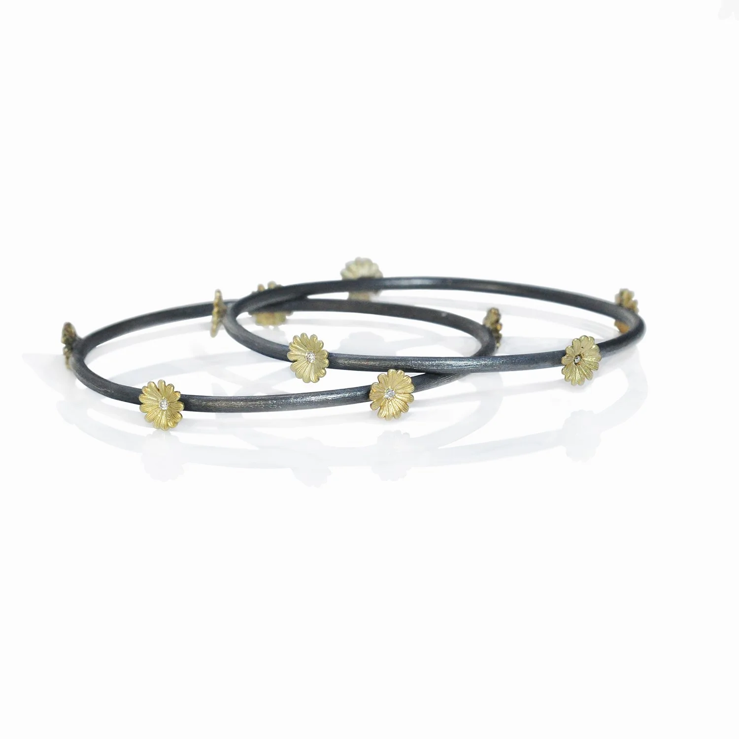 Shasta Daisy Bangles. 14k yellow gold, white diamonds, oxidized silver. Bracelet on white background. Handmade fine art jewelry by Rebecca Myers Design.