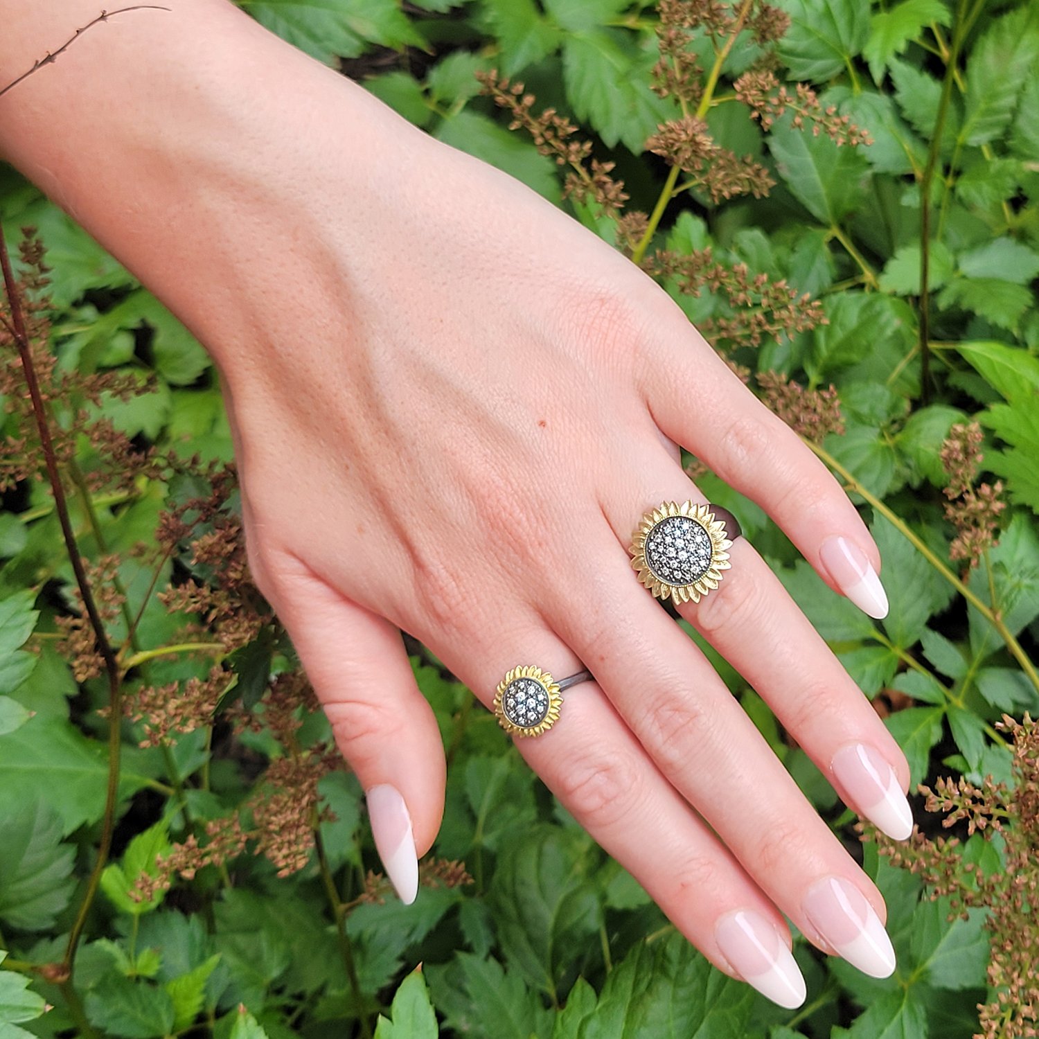 Pave Diamond Sunflower Rings. 14k yellow gold, oxidized silver, pave set white diamonds. Shown here on white female model. Handmade fine art jewelry by Rebecca Myers Design.