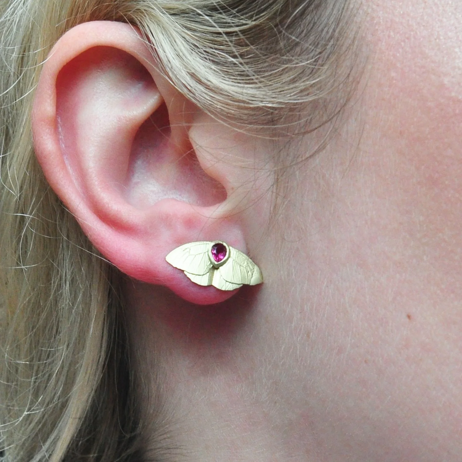 Small Gold Butterfly Earrings. 14k yellow gold, pear shaped rubies. Shown on white female model. Handmade fine art jewelry by Rebecca Myers Design.