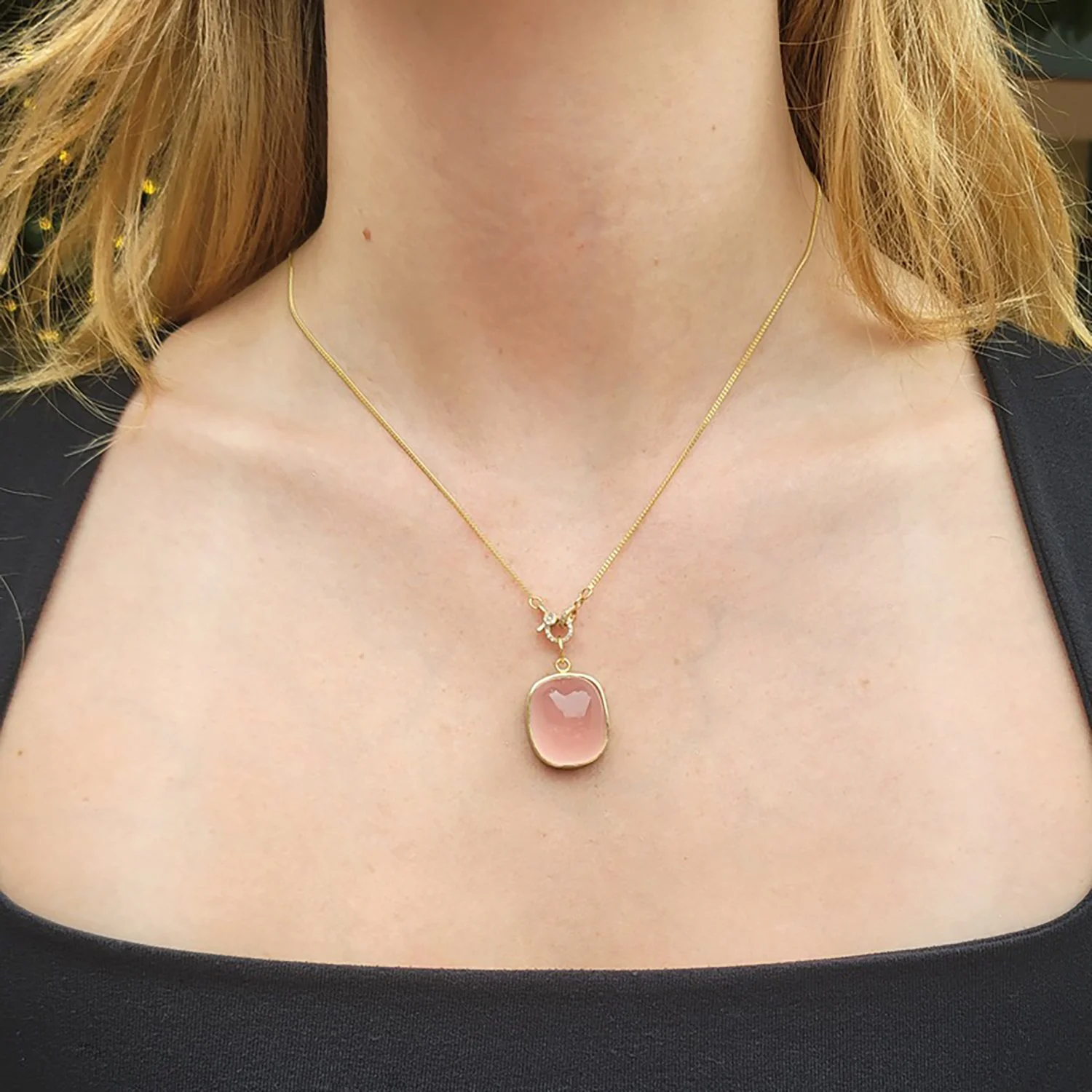 Large Rose Quartz Cab Charm necklace. Cushion cut rose quartz cabochon, 18k yellow gold, silver, 14k yellow gold chain. Shown on white female model. Handmade fine art jewelry by Rebecca Myers Design.