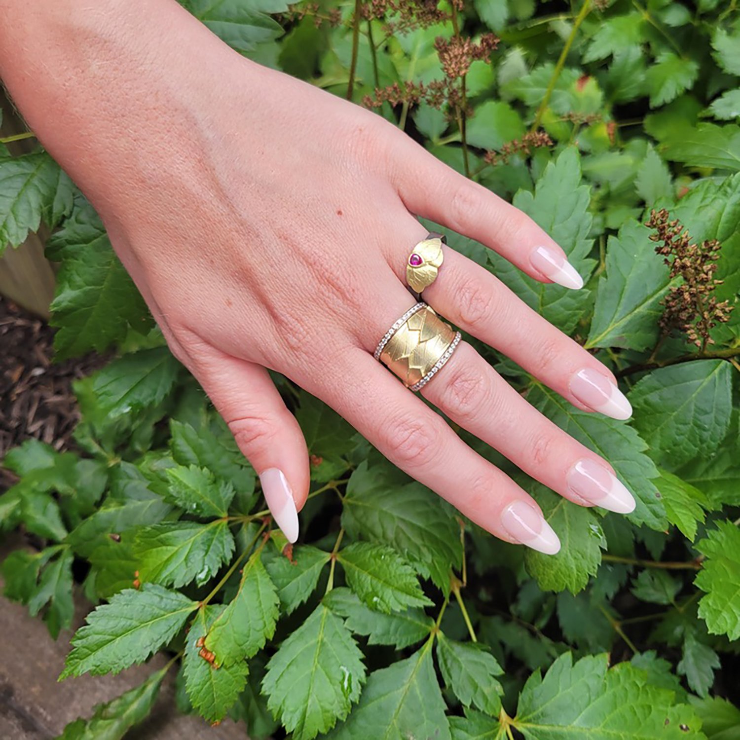 Small Gold Butterfly Ring. 14k yellow gold, oxidized silver, pear shaped ruby. Shown here on white female model. Handmade fine art jewelry by Rebecca Myers Design.