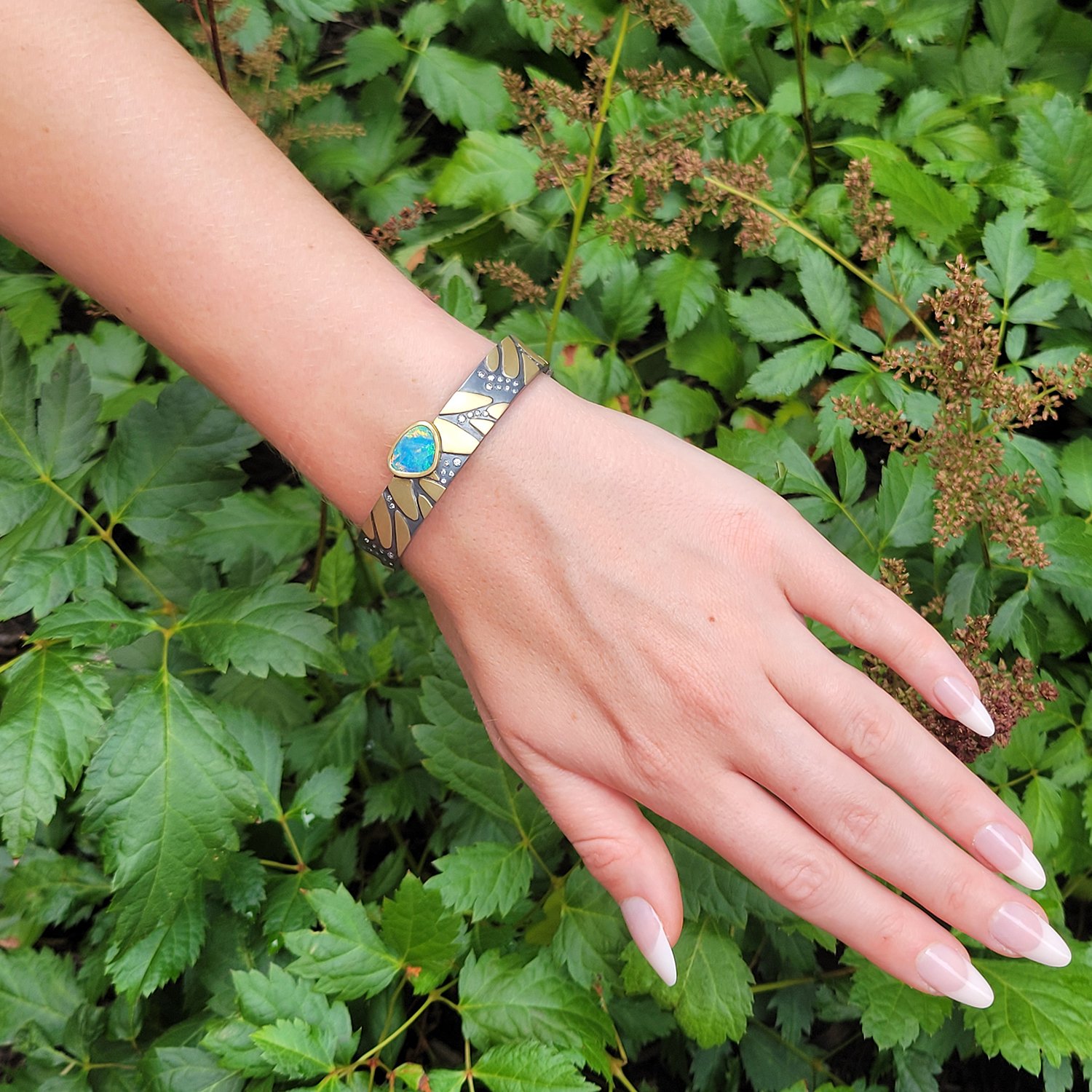 Monarch Print Hinged Bracelet with Boulder Opal. 18k yellow gold, oxidized silver, diamonds, boulder opal. Shown here on white female model. Handmade fine art jewelry by Rebecca Myers Design.