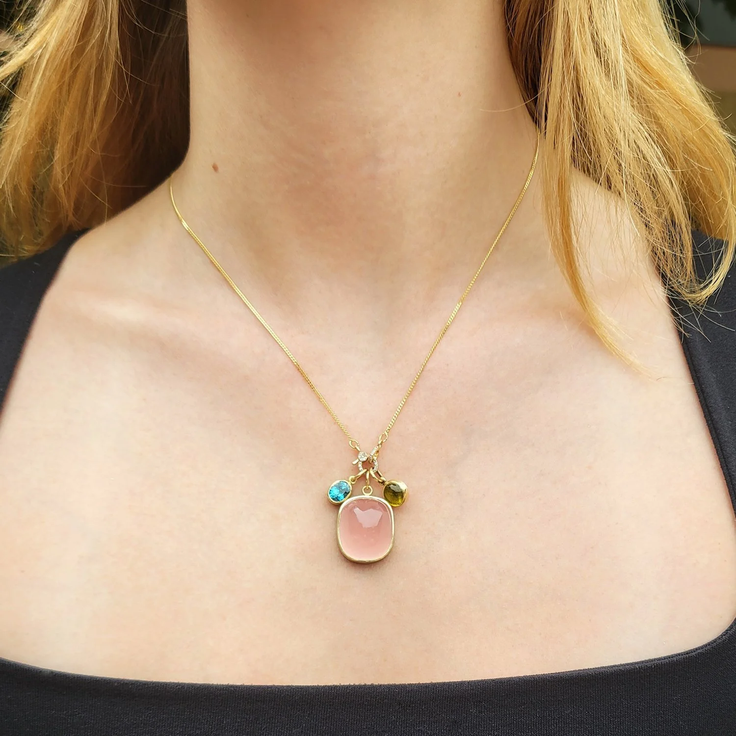 Blue Zircon + Cushion Rose Quartz + Yellow Tourm Charms on 14k yellow gold chain. Shown on white female model. Handmade fine art jewelry by Rebecca Myers Design.