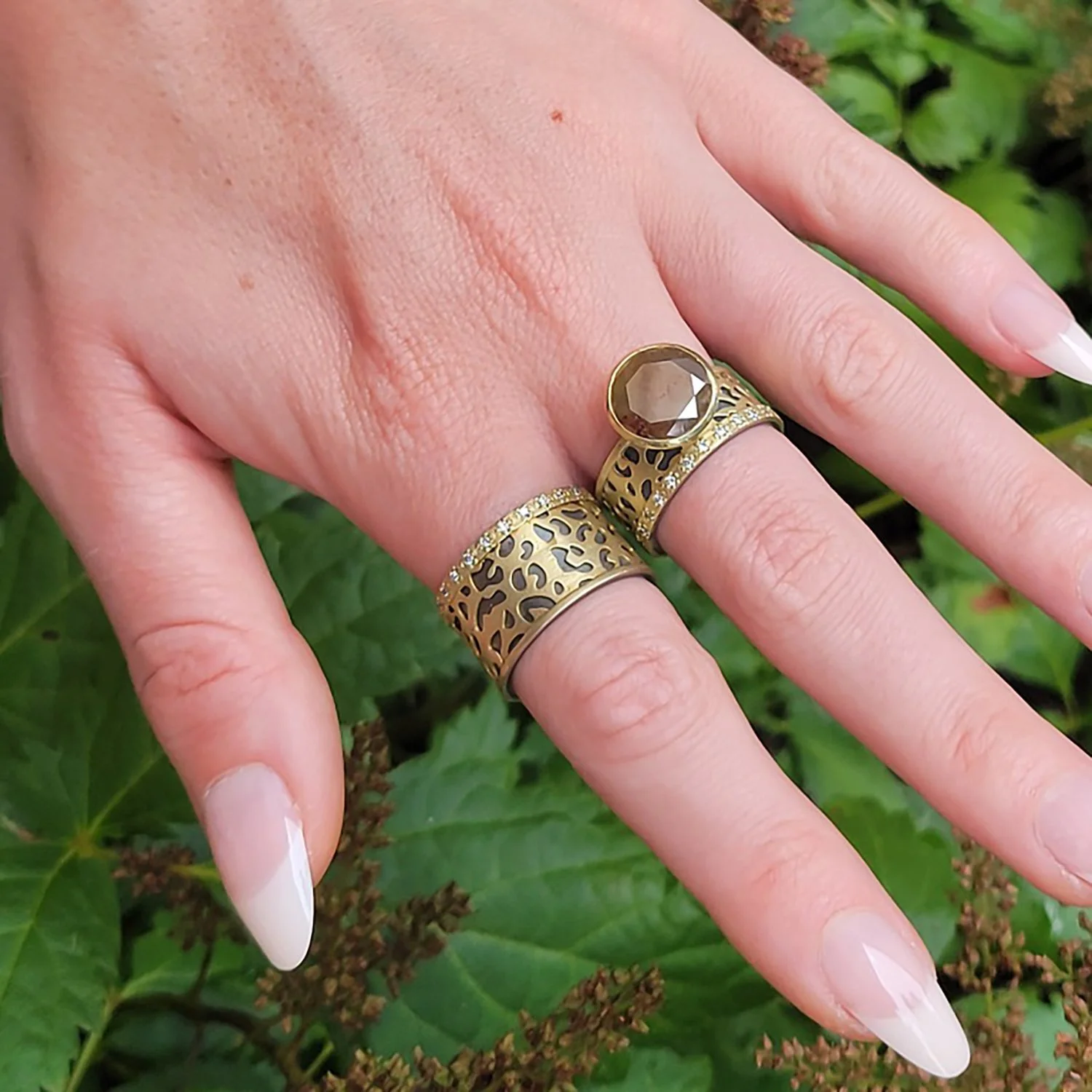 Cheetah Rings. 18k yellow gold, oxidized silver, pave set diamonds, large round brown raw diamond. On white female model. Handmade fine art jewelry by Rebecca Myers Design.
