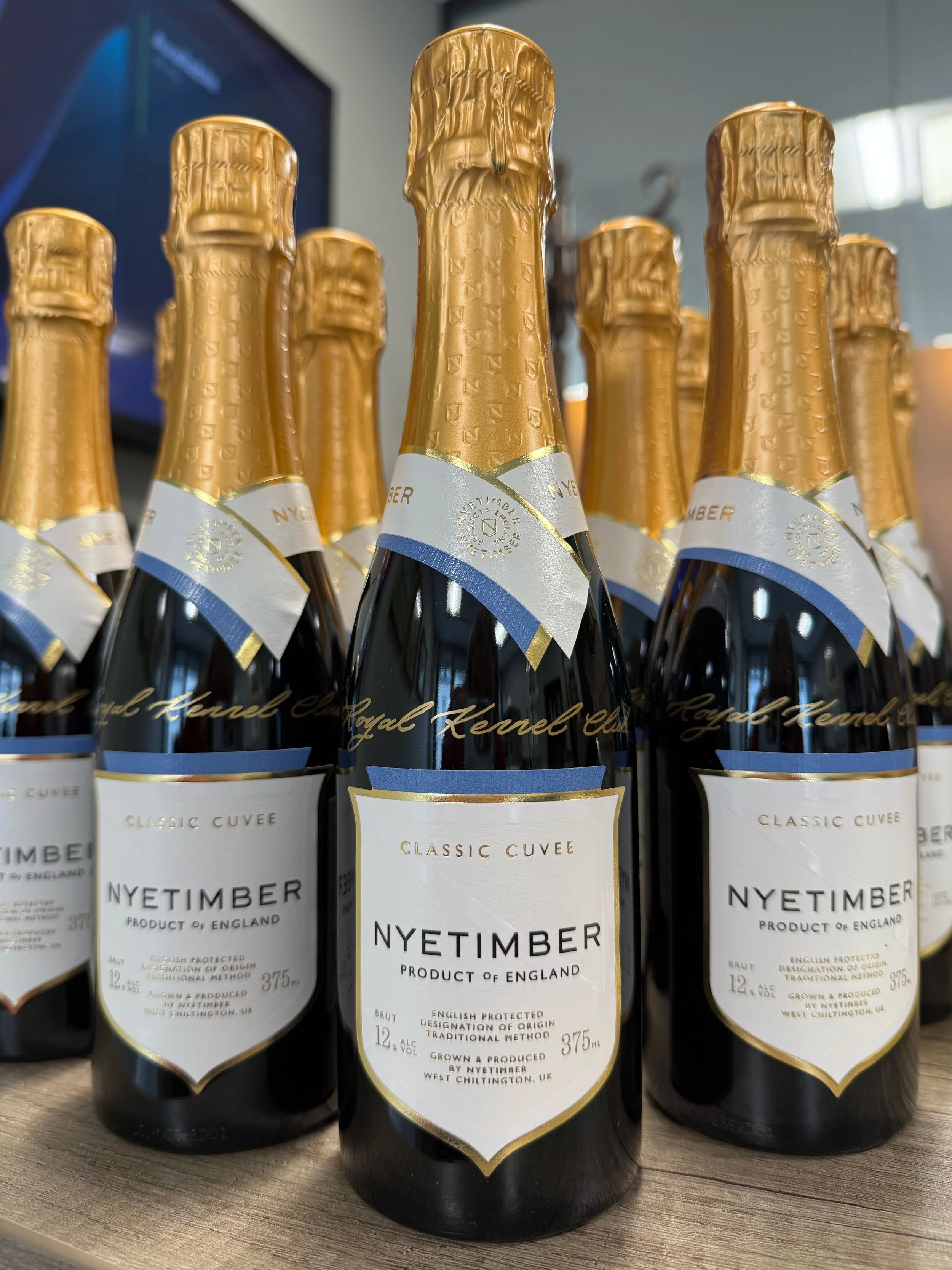 Corporate gifting of NYETIMBER bottles for The Royal Kennel Club with calligraphy personalisation of the english sparking wine bottles. Champagne live event calligraphy personalisation. Client gifting. Personalised wine.