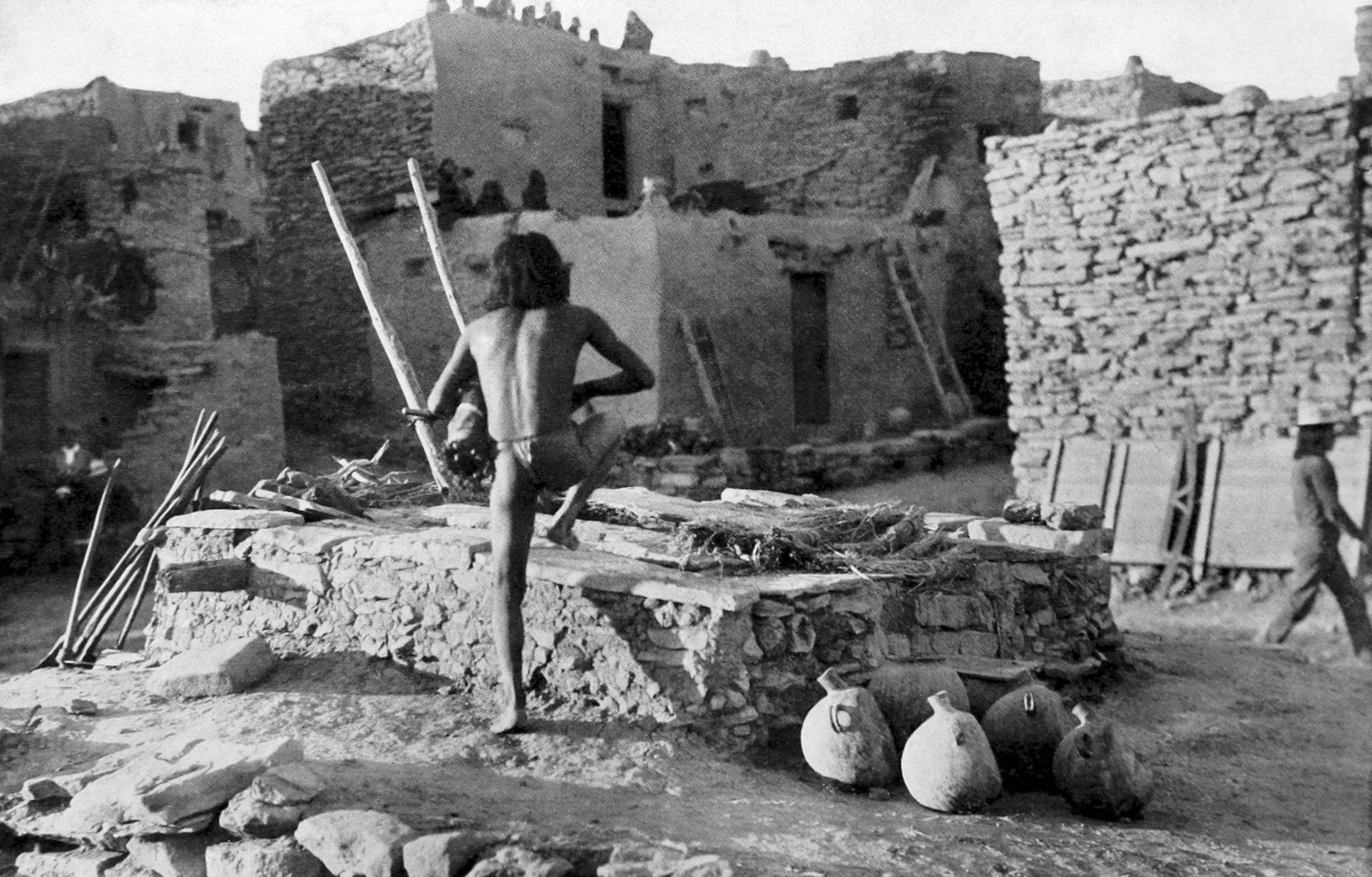 A dancer returning to the kiva with his Snake costume after having released a handful of snakes