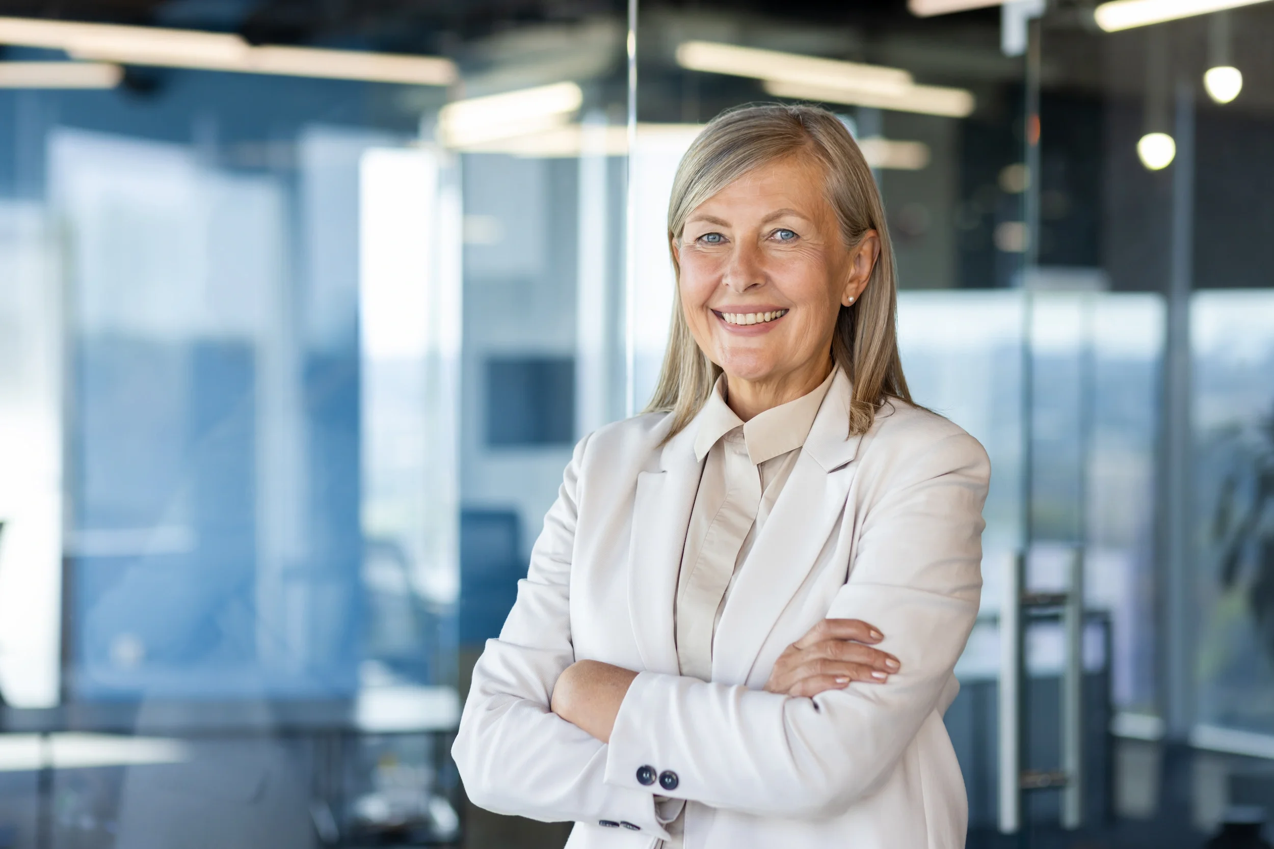 Smiling senior businesswoman with arms folded in a modern glass office, representing the industry leaders an executive coach services, in a Beauxhaus website, SEO and  GEO case study