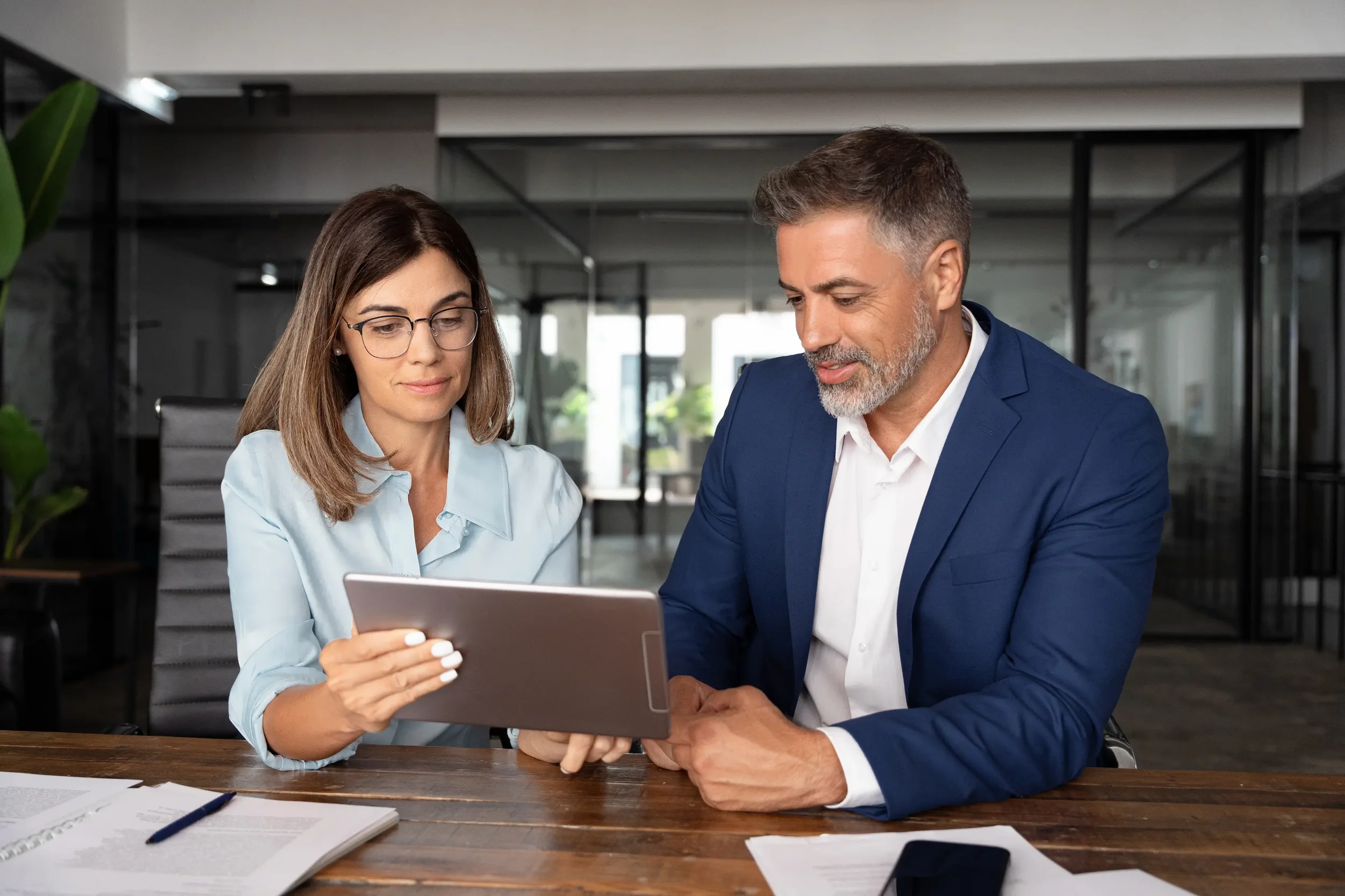 Two professionals reviewing a tablet together in an office