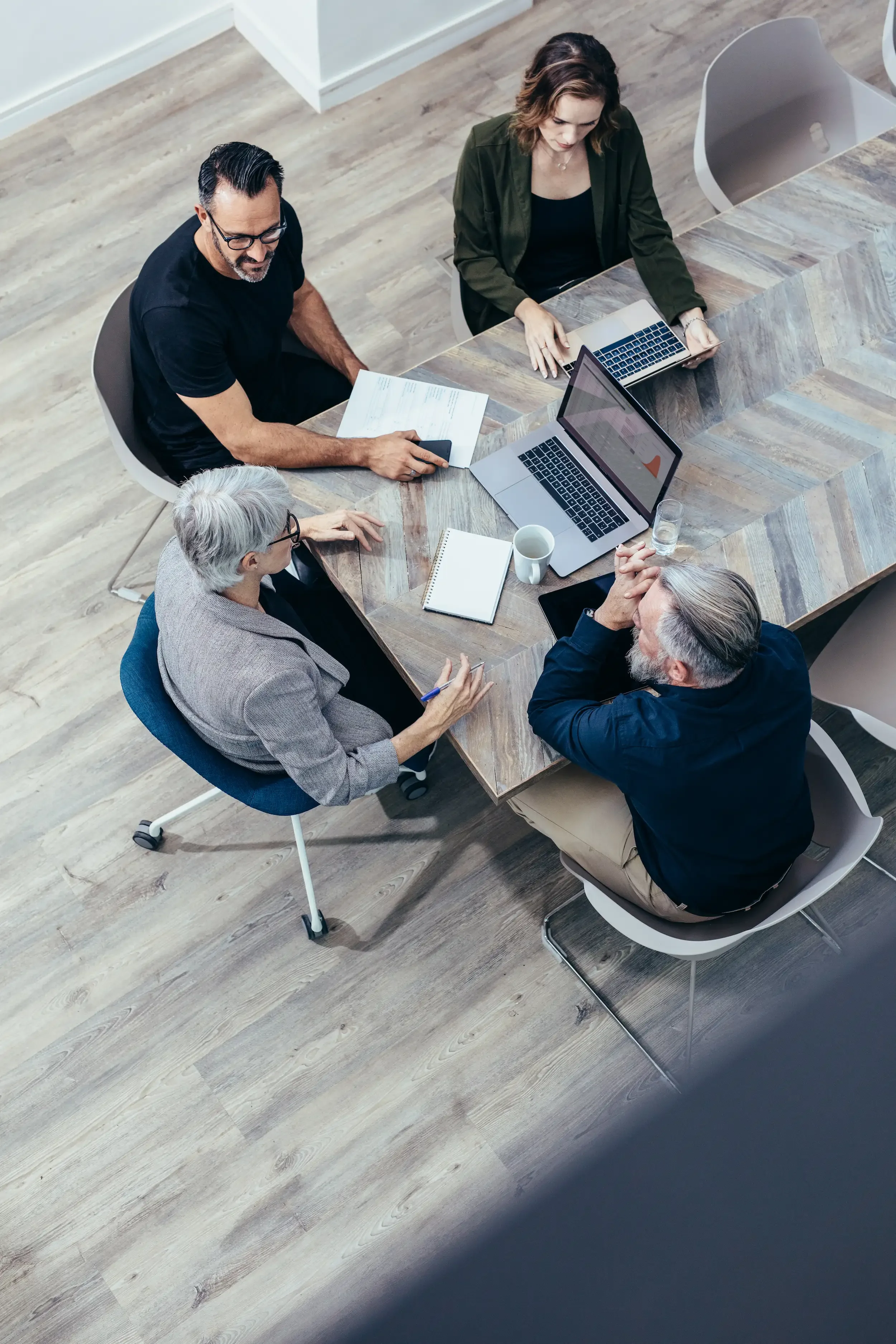 Four professionals discuss SEO copywriting strategy around a table with laptops and notepads