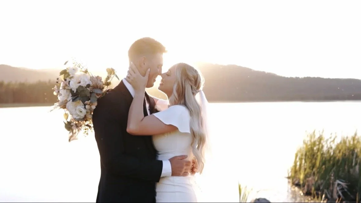 A bride and groom standing in front of a lake at golden hour in Island Park, Idaho.