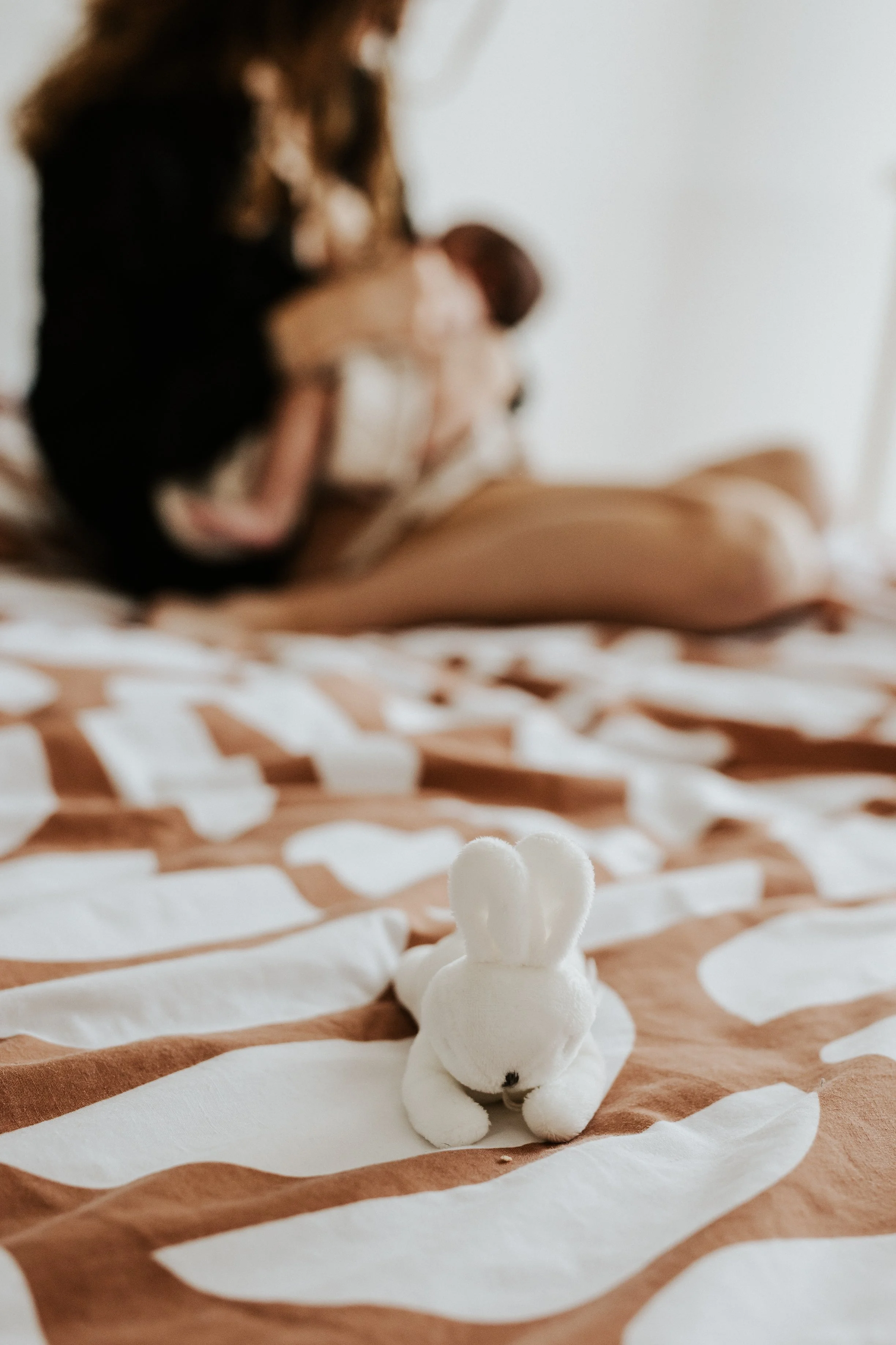 photo intimiste d'une maman flou en train d'allaiter son nouveau né sur son lit