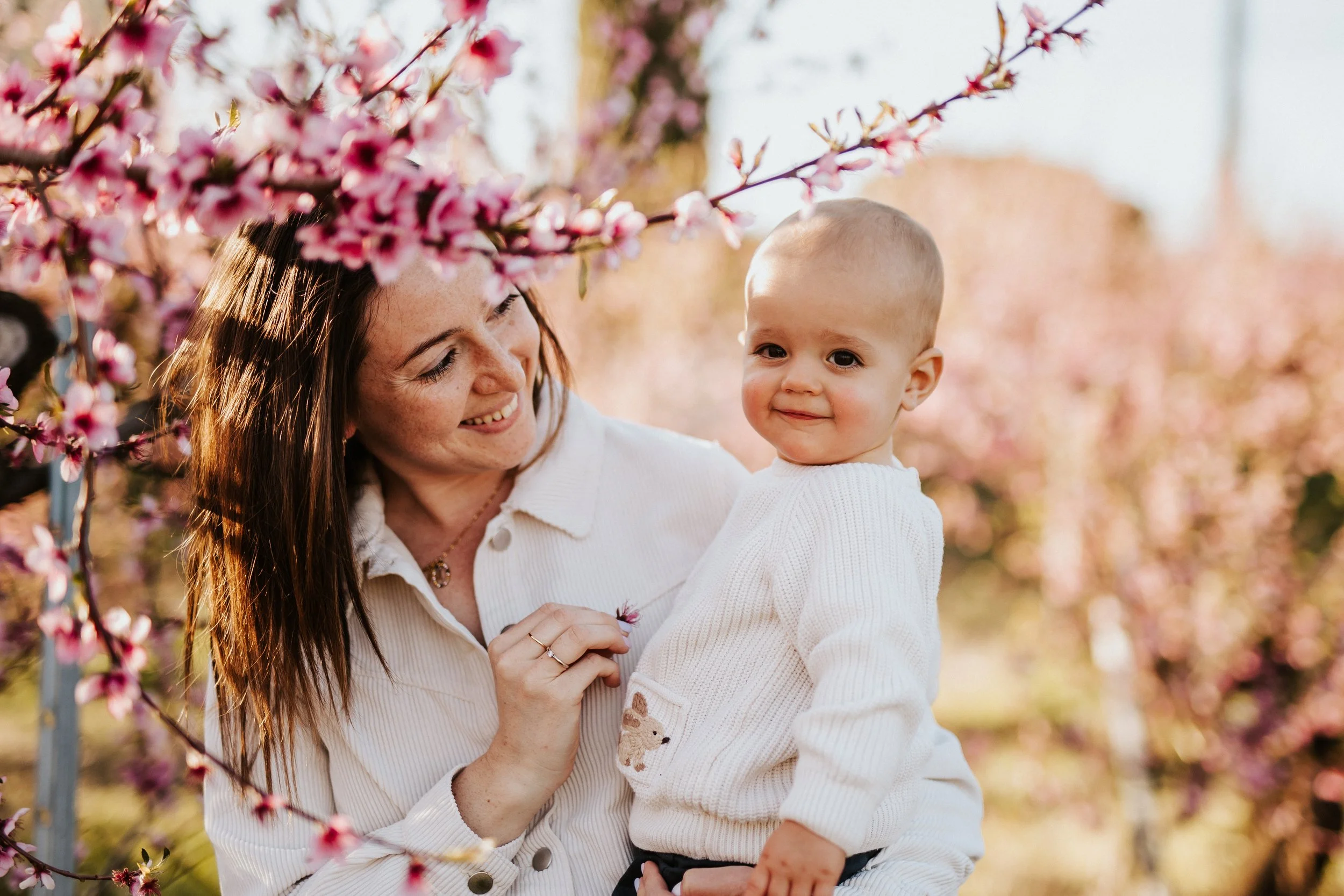Séance photos sous les pêchers en fleurs au printemps dans le Beaujolais : retrouver O. et a. pour un moment maman-bébé
