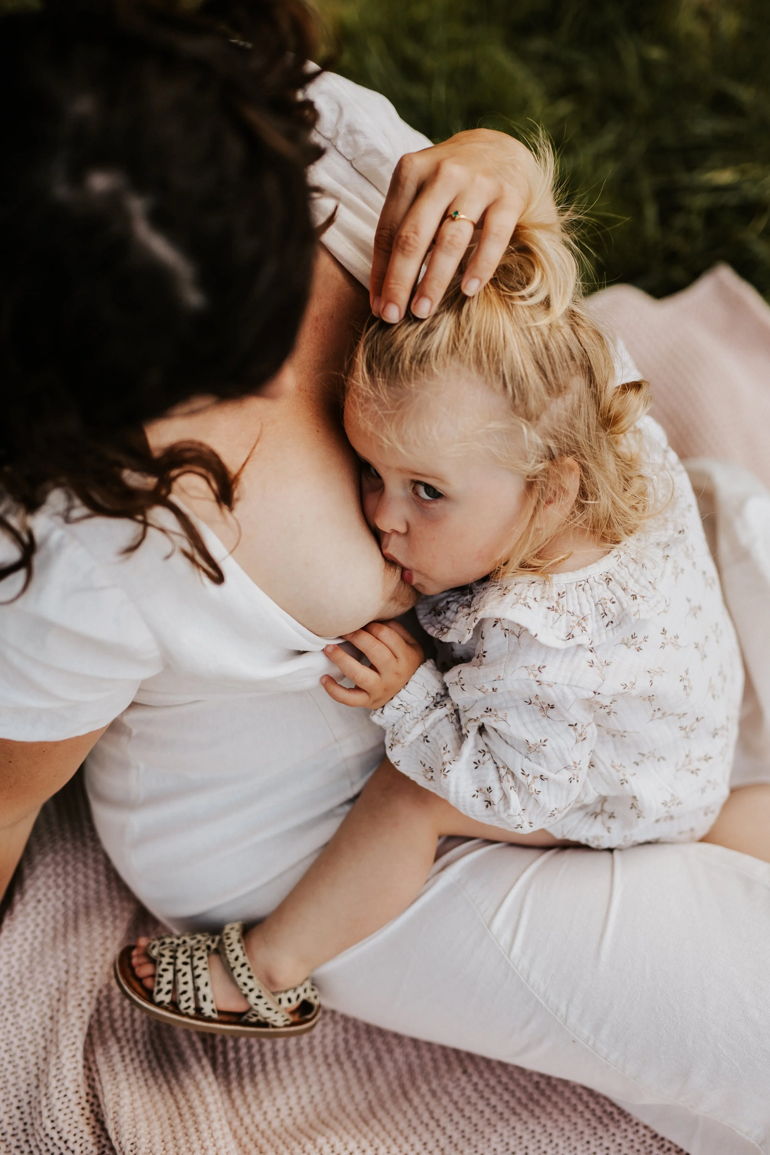 photo de la main de maman qui carresse la tête de bébé pendant ce moment allaitement tout doux en pleine nature près de Lyon