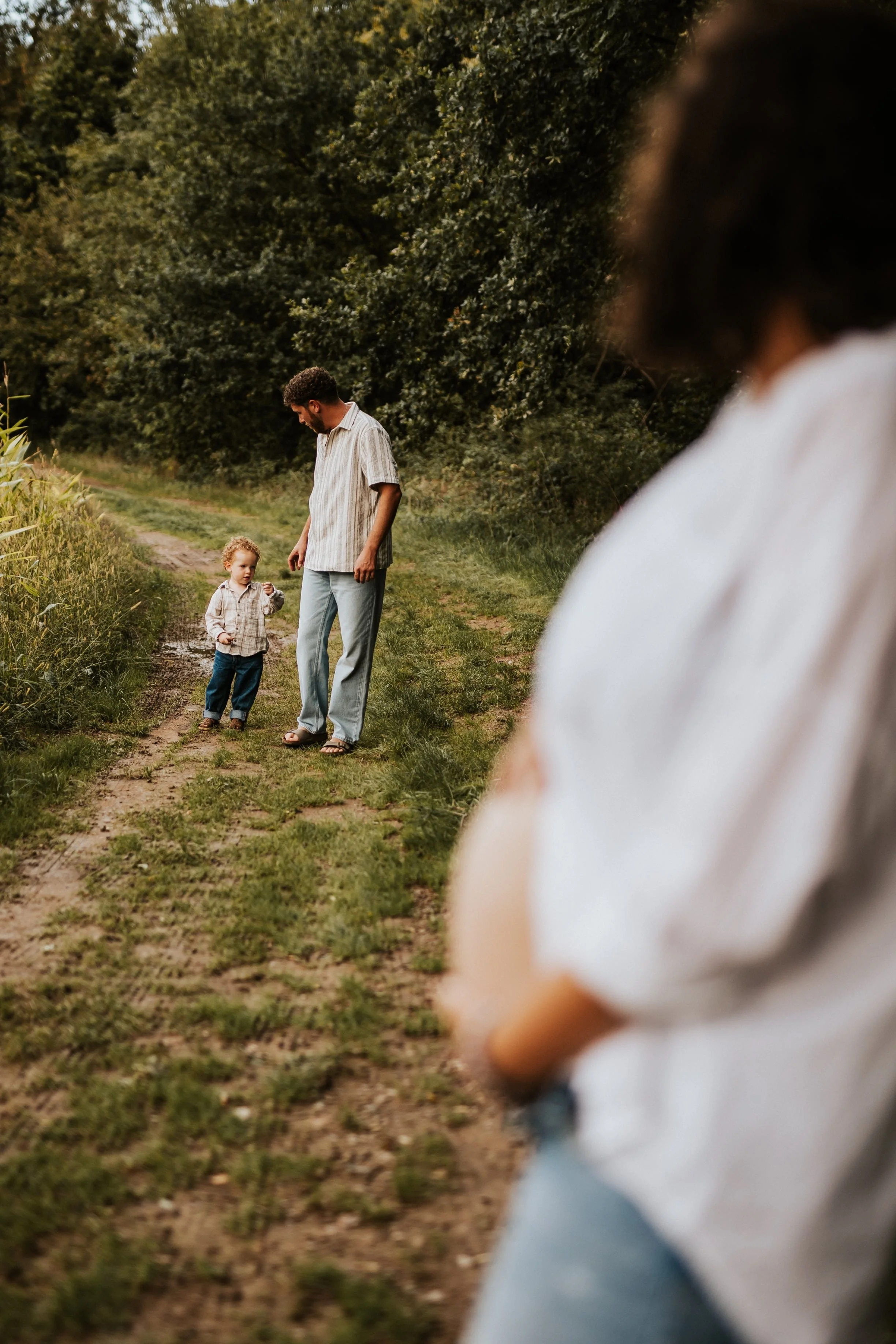 photo du ventre d'une future maman flou devant le papa et le futur grand frère pendant une séance grossesse dans la nature du beaujolais