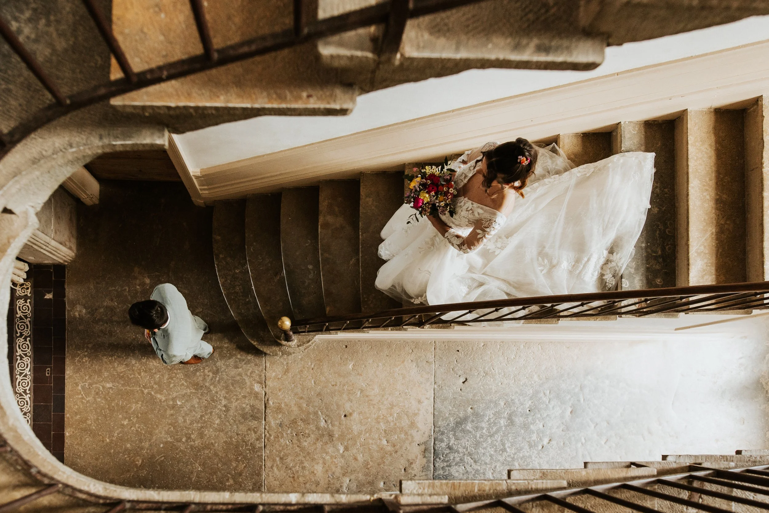 la mariée rejoint le marié pour le first look dans l'escalier majestueux du domaine de tourieux à Savigny