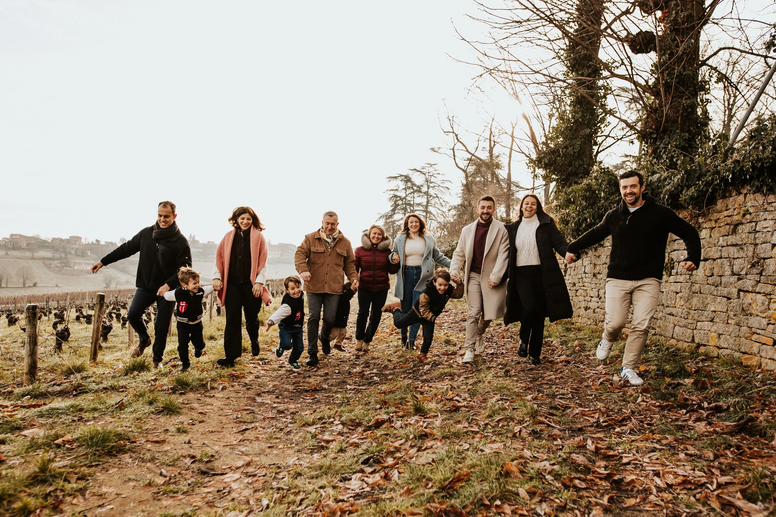 photos d'une famille nombreuse et intergénérationnelle courant tous ensemble dans les vignes du beaujolais