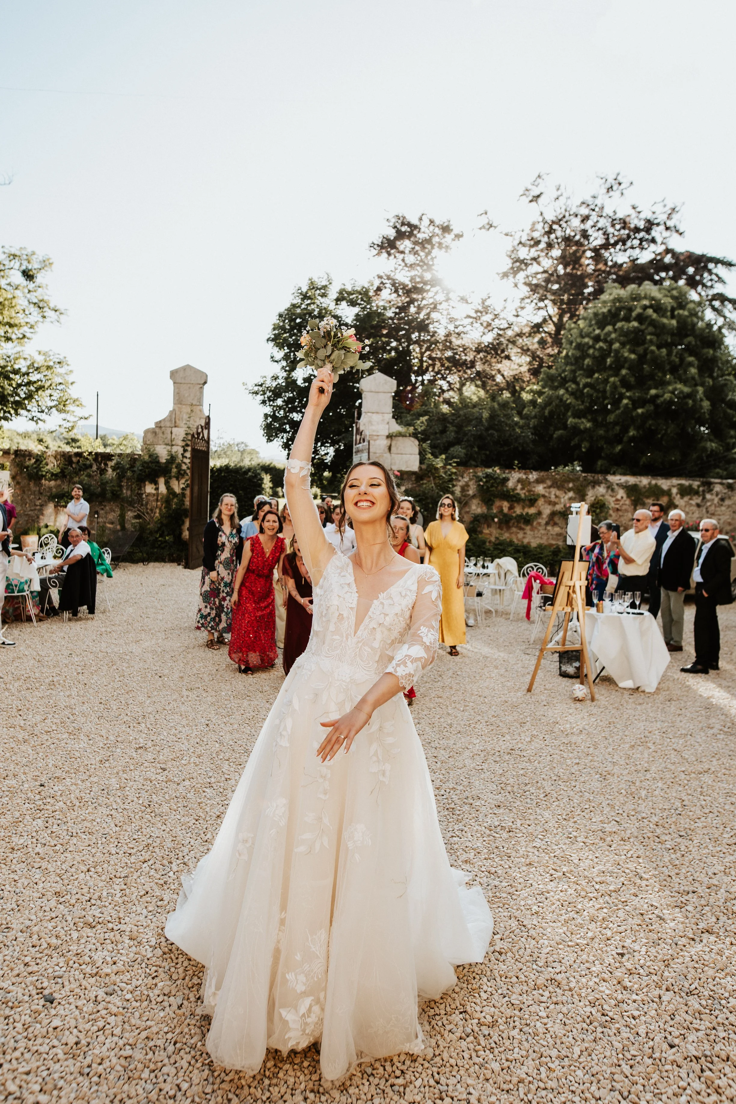 photo du lancer de bouquet de la mariée pendant le cocktail dans la cour du domaine de tourieux