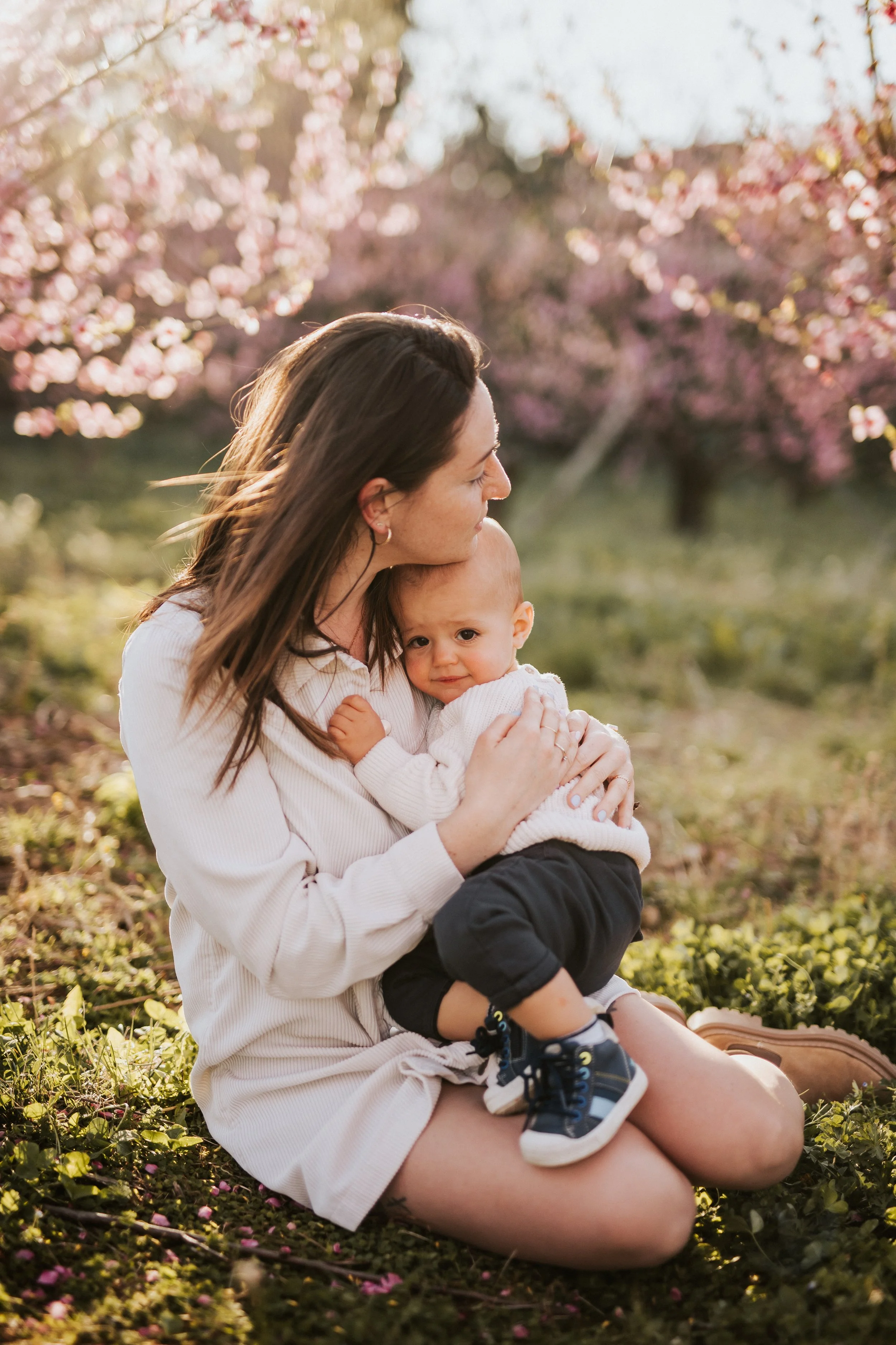 photo d'un calin maman et bébé sous un prunier rose en fleurs dans le beaujolais