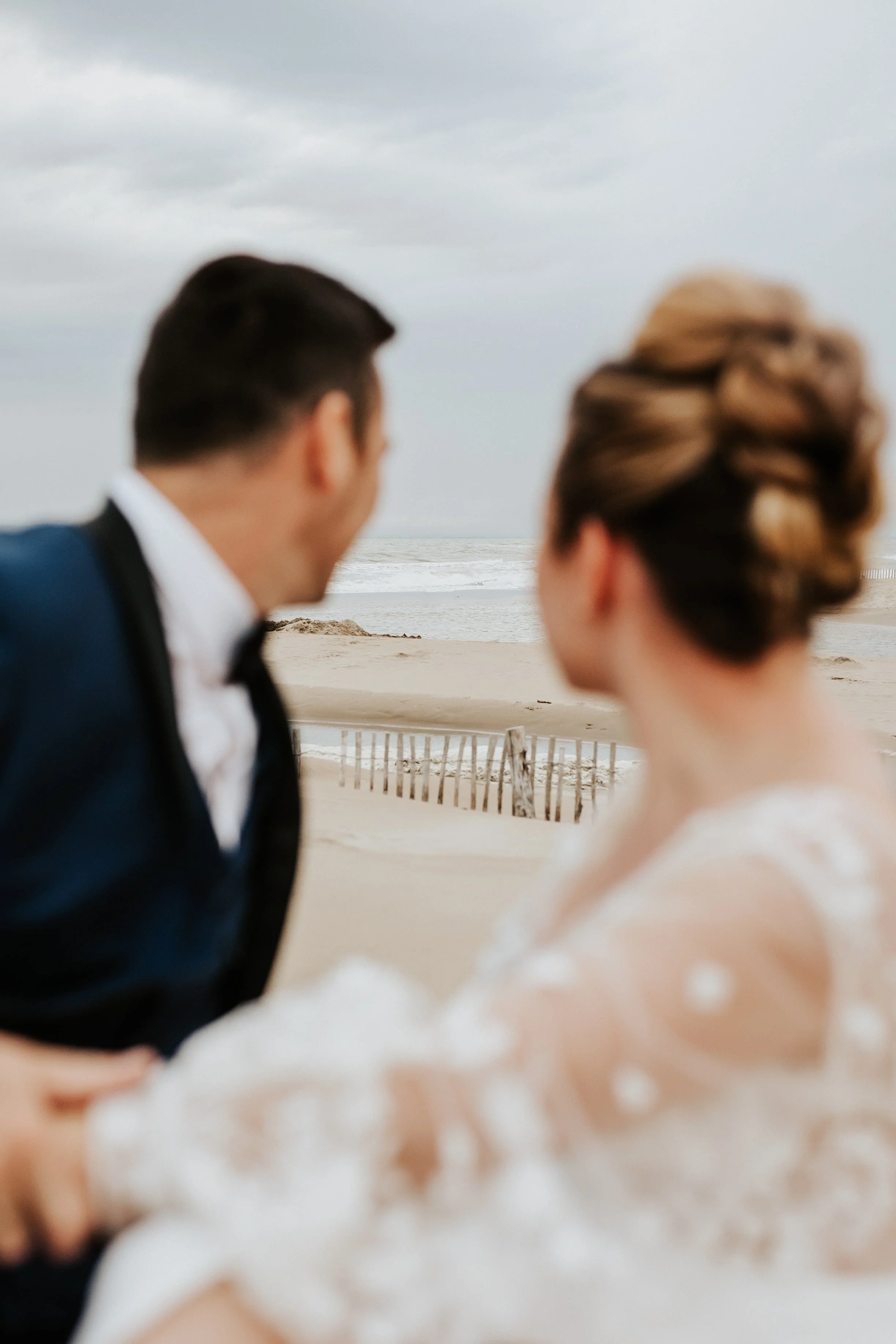 mariés flous qui regardent la mer pendant leur séance day after à la plage