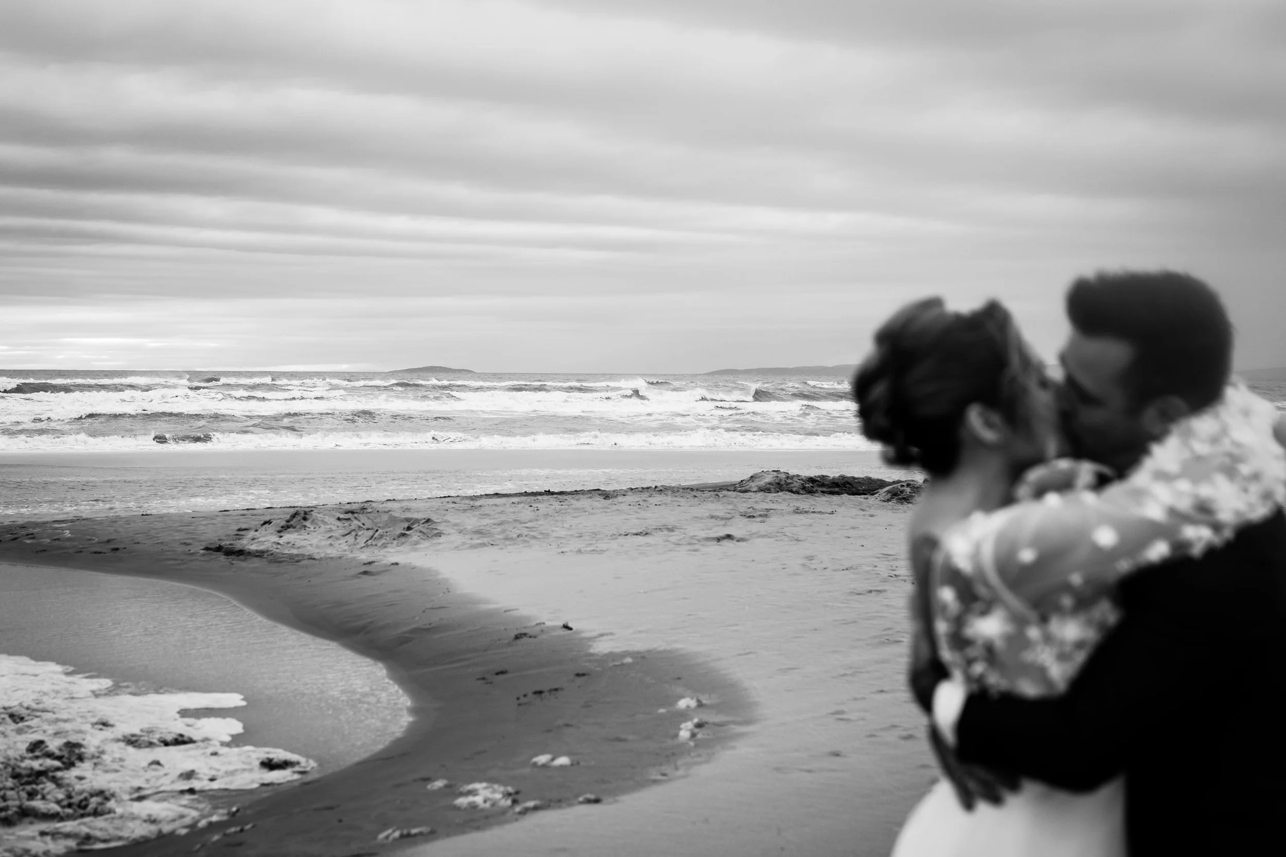 paysage de la plage en noir et blanc avec mariés flous en train de s'embrasser