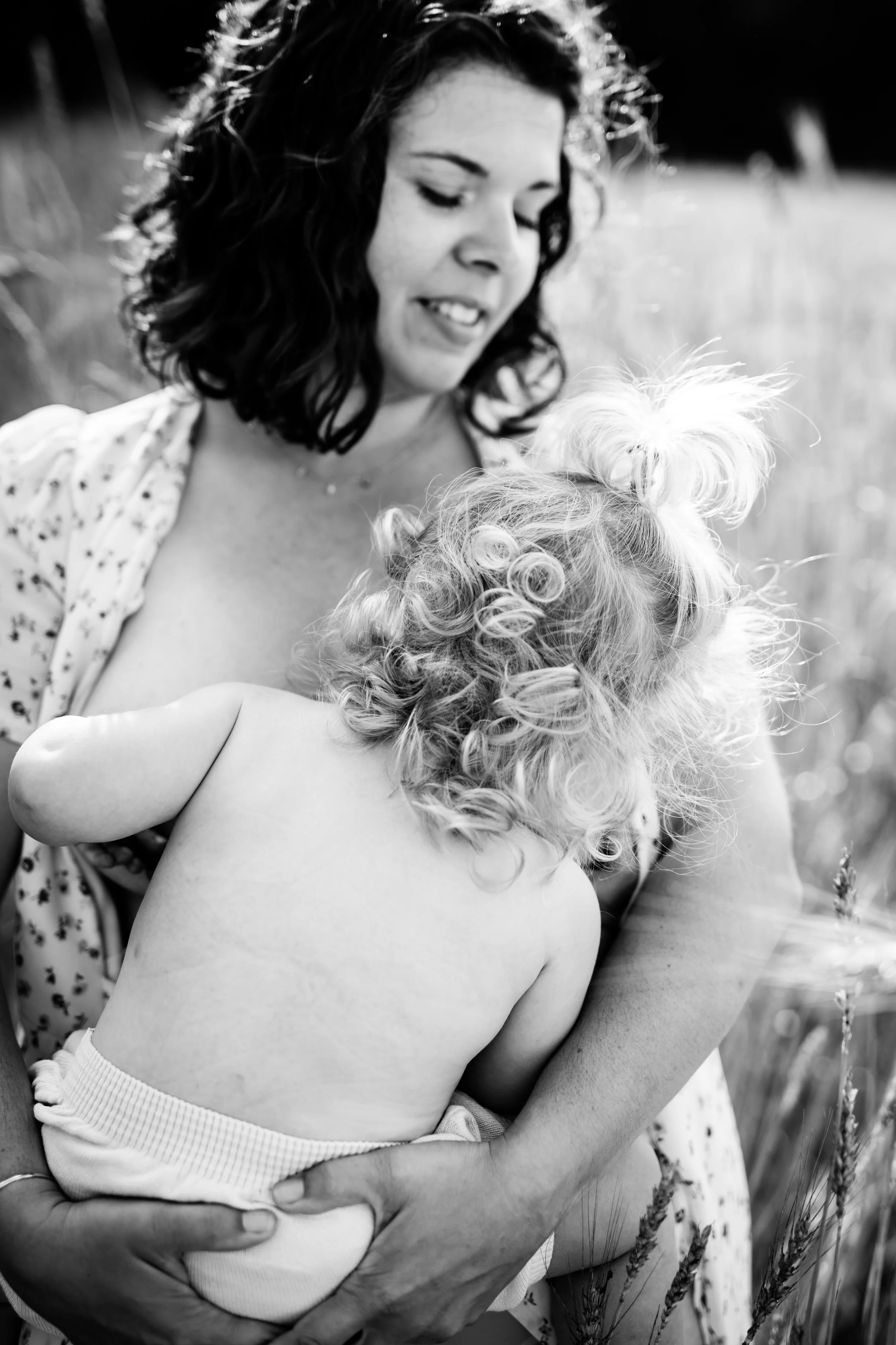 photo noir et blanc de maman allaitant debout dans le champs de blé à la jolie lumière d'un après midi d'été près de Lyon