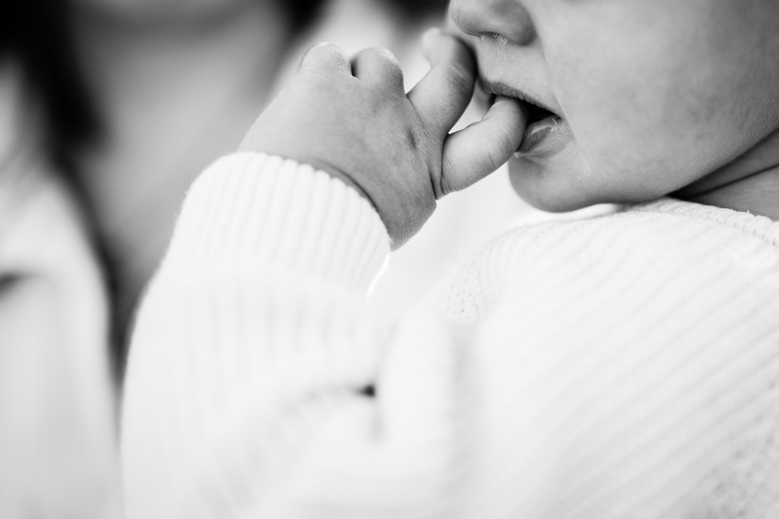 photo de détails en noir et blanc d'une main de bébé dans sa bouche