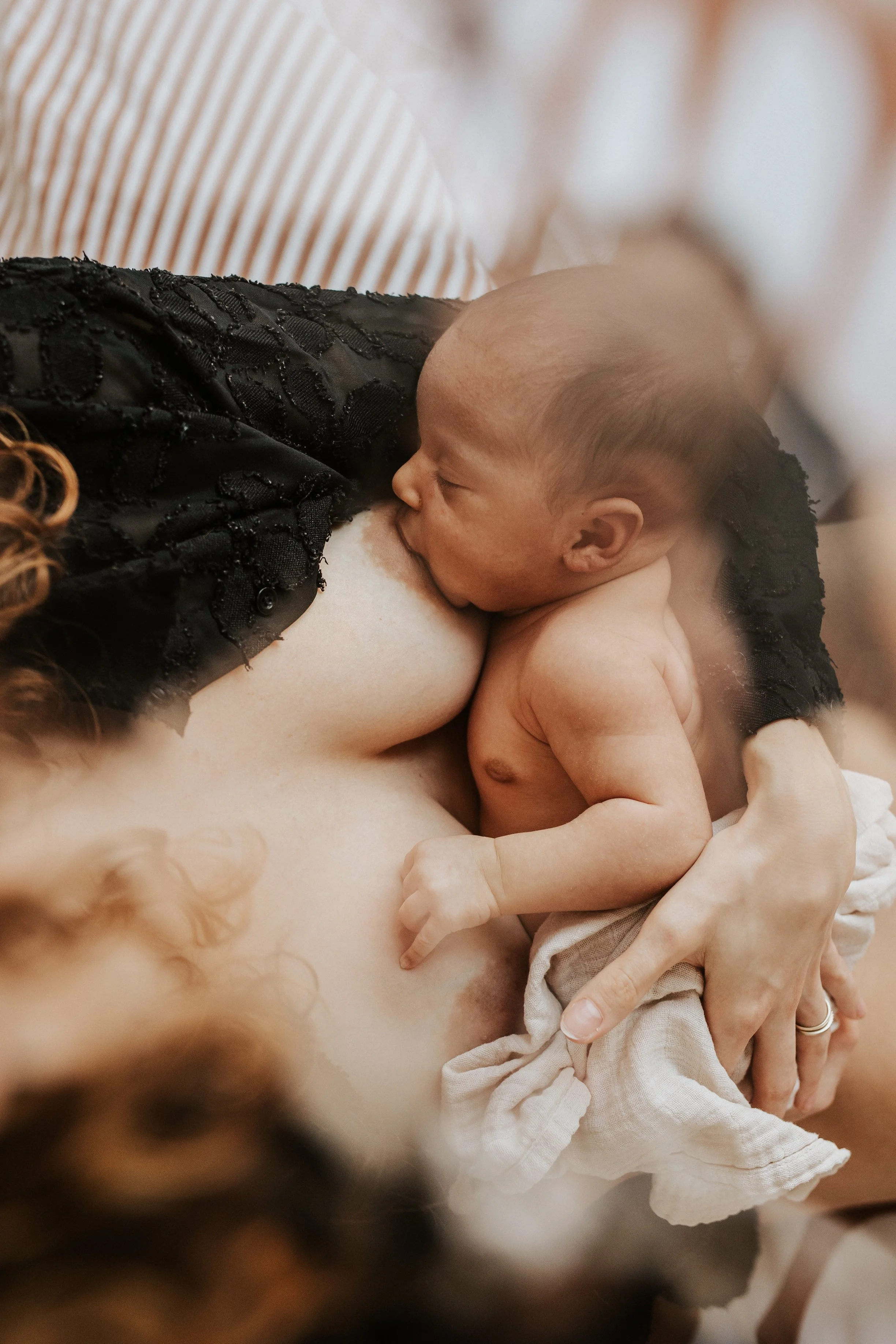 photo d'un bébé en train d'être allaité à domicile dans la chambre parentale avec des effets de flou esthétique