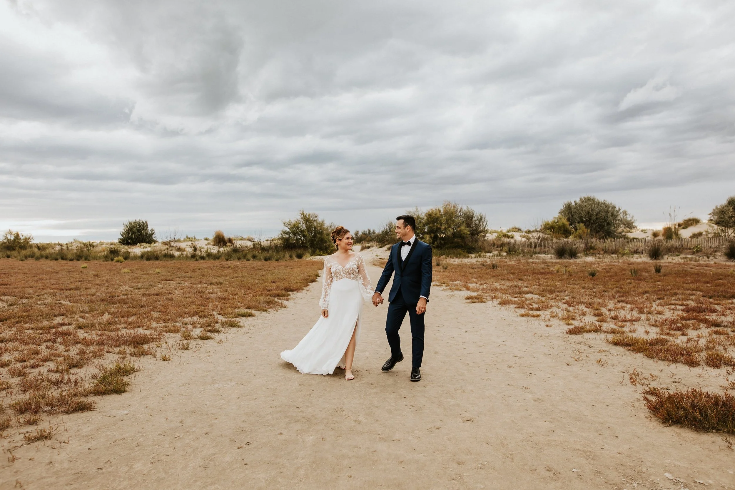 couple de marié en séance après le mariage sur le chemin de la plage au grau du roi