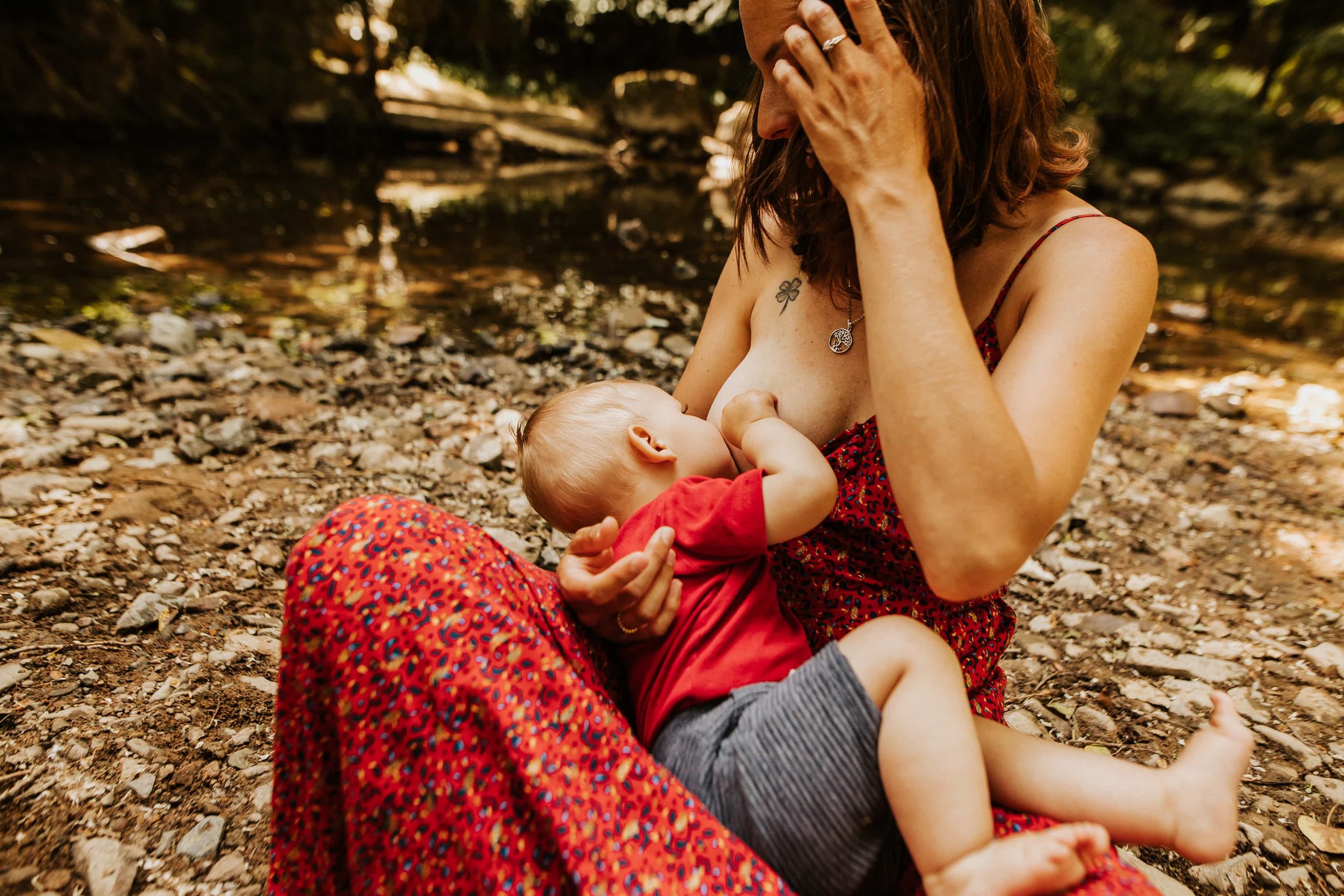 photo d'une maman allaitant au bord d'une rivière lors de sa séance photo en plein été à côté de Lyon