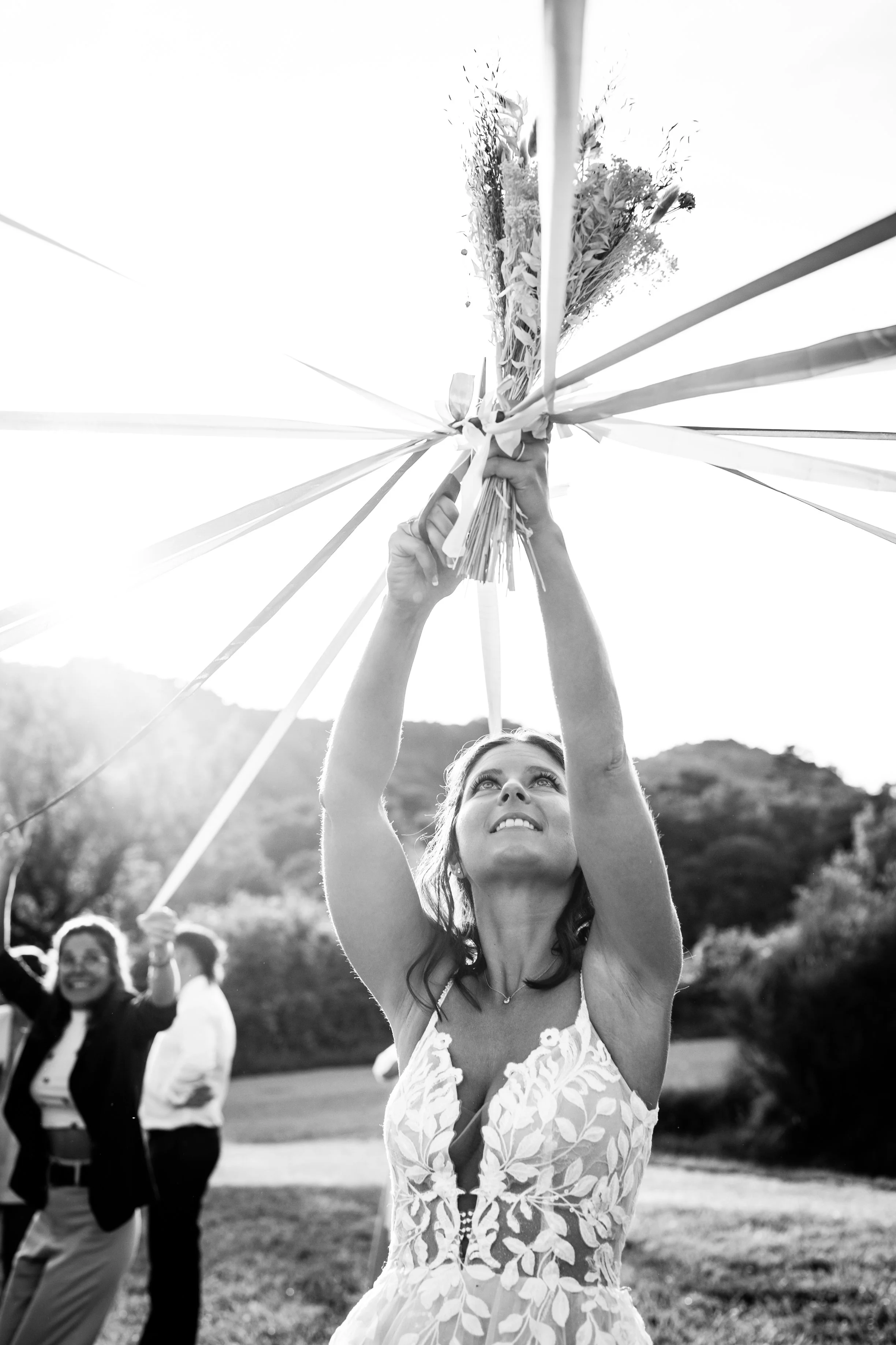 photo d'une mariée en pleine ronde de rubans pour son bouquet au coucher de soleil en provence