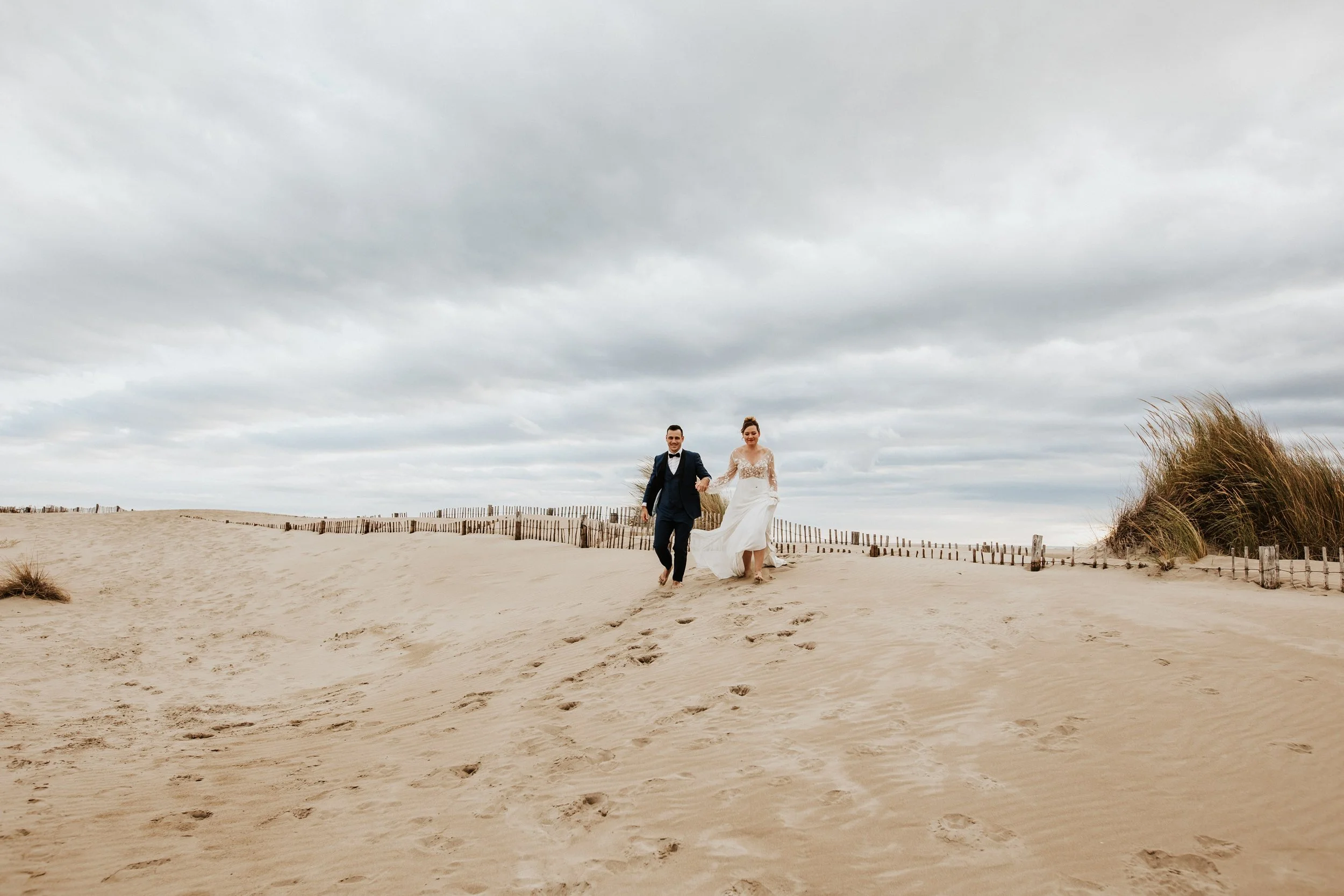couple courant dans les dunes de sable pendant leur séance après leur mariage près de montpellier