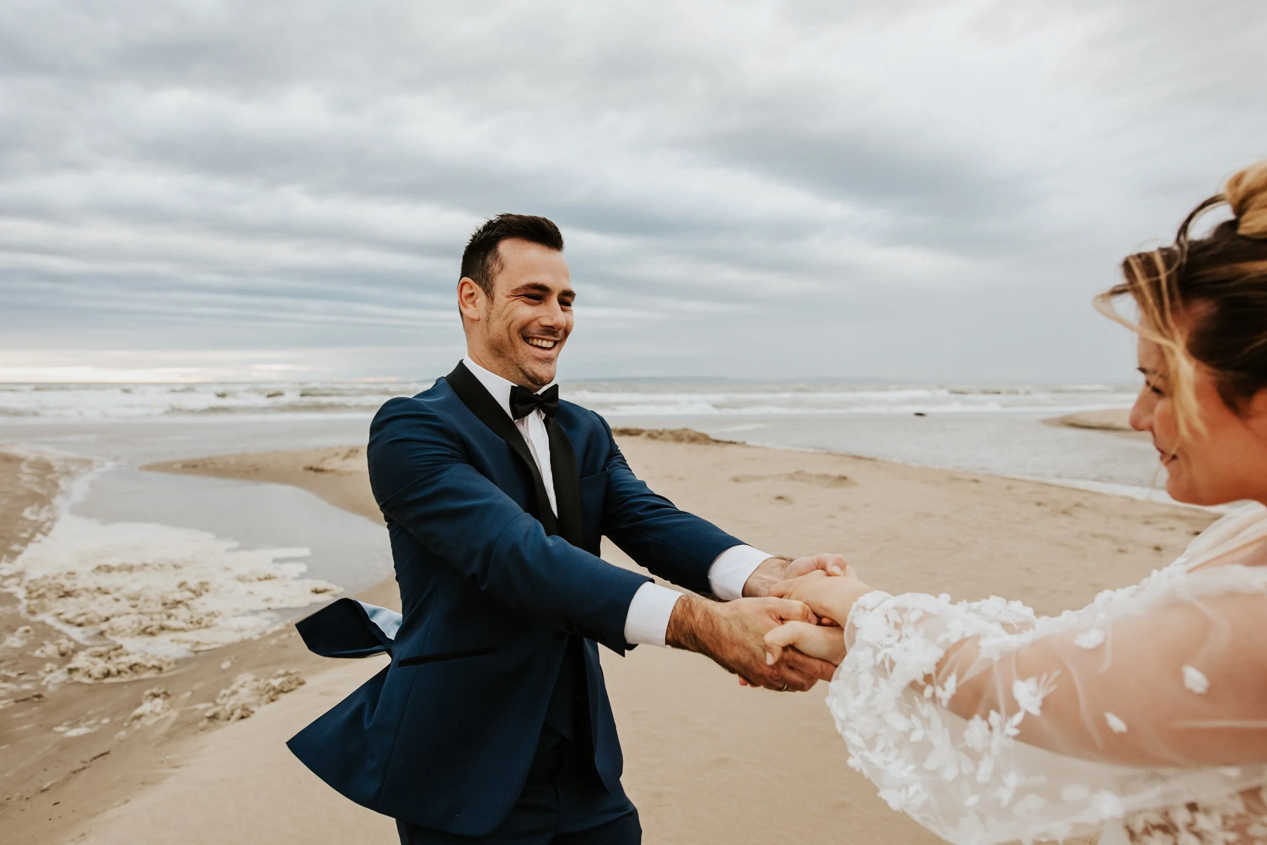mariés qui jouent dans le vent au bord de l'eau sur la plage de l'espiguette du grau du roi