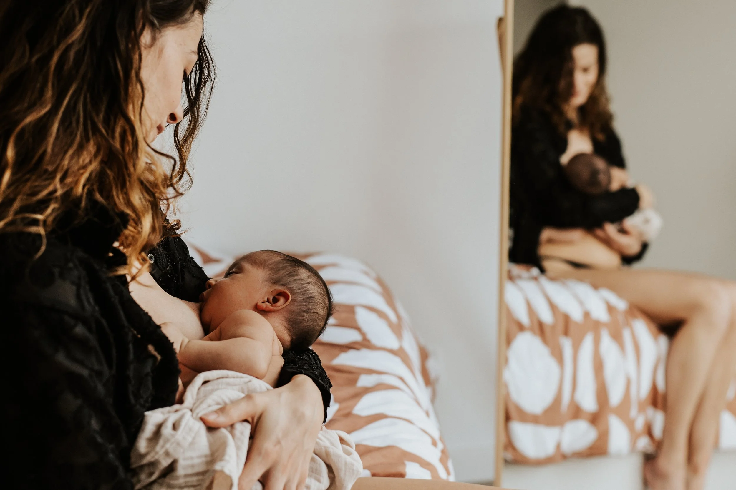 photo d'une maman en train d'allaiter son bébé dans le reflet de son miroir à domicile à Lyon