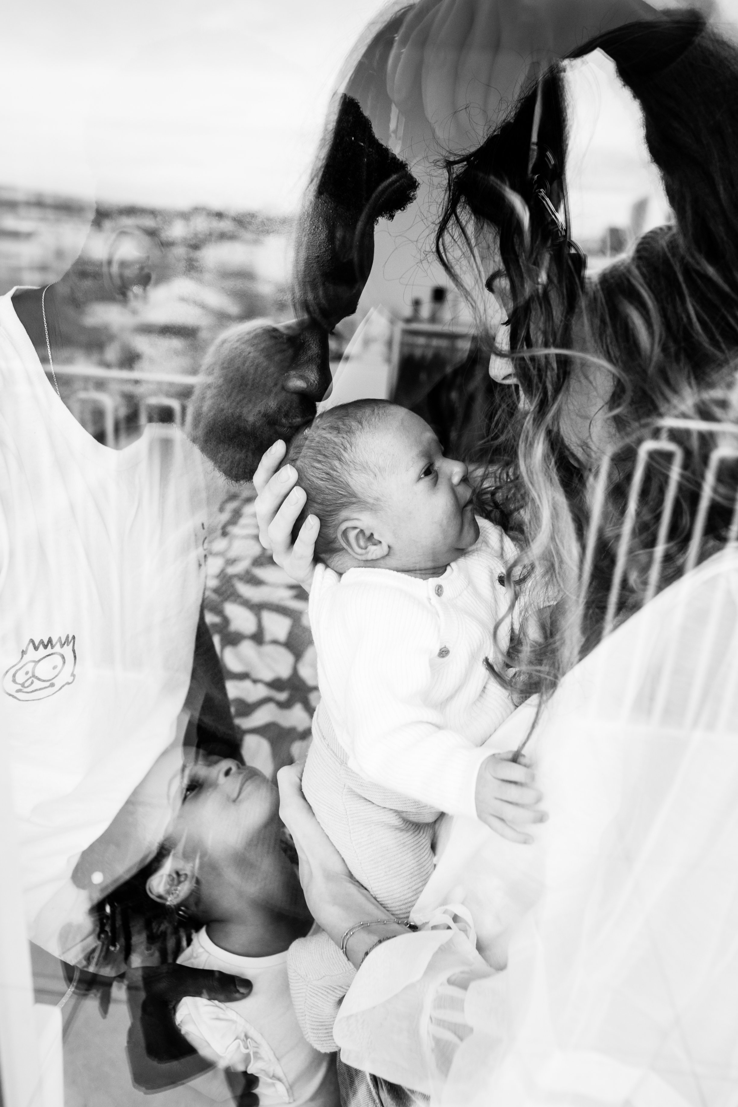 photo noir et blanc d'une famille à travers une fenêtre avec le reflet de Lyon