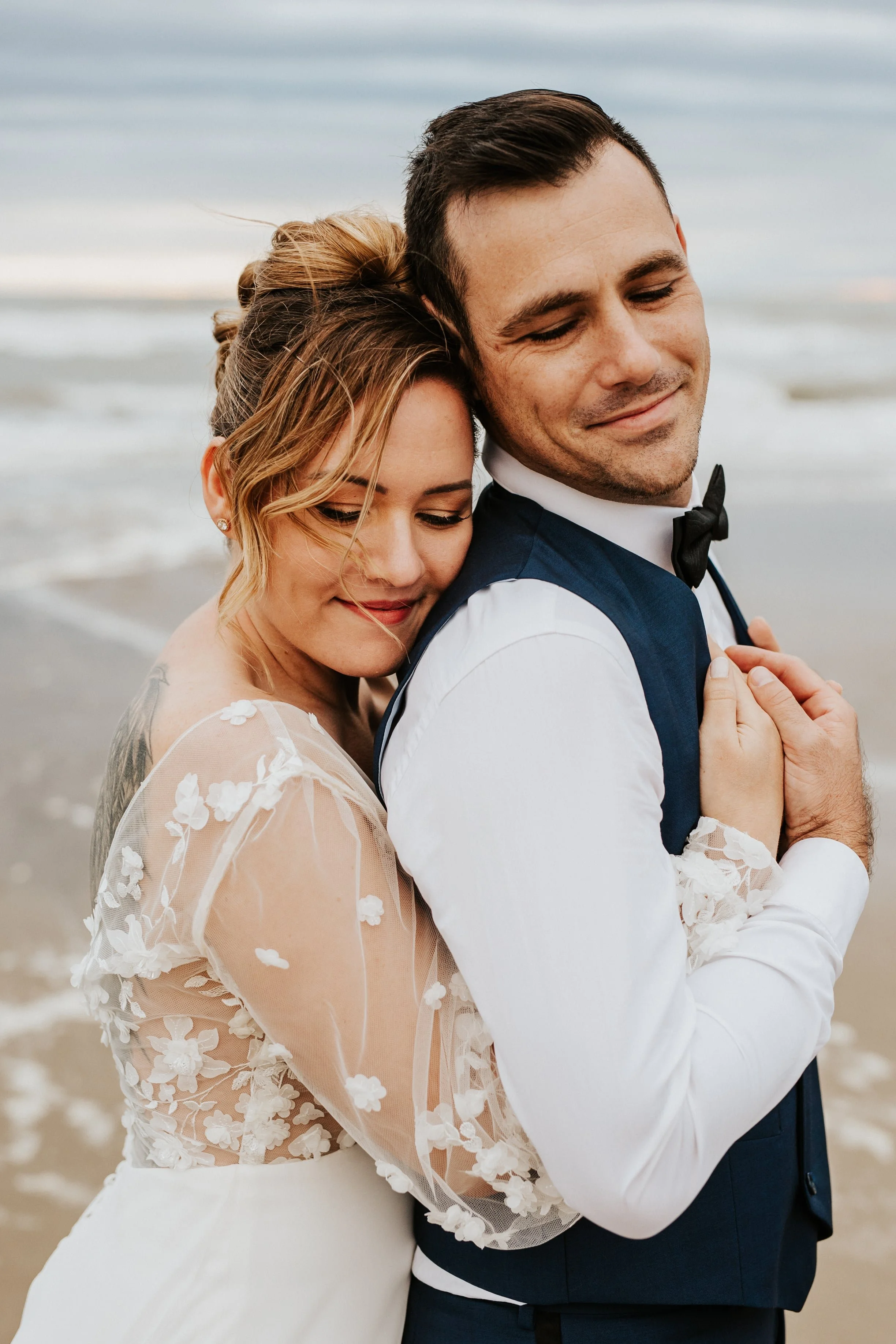 mariée qui enlace tendrement son mari les pieds dans l'eau à la plage près de Montpellier