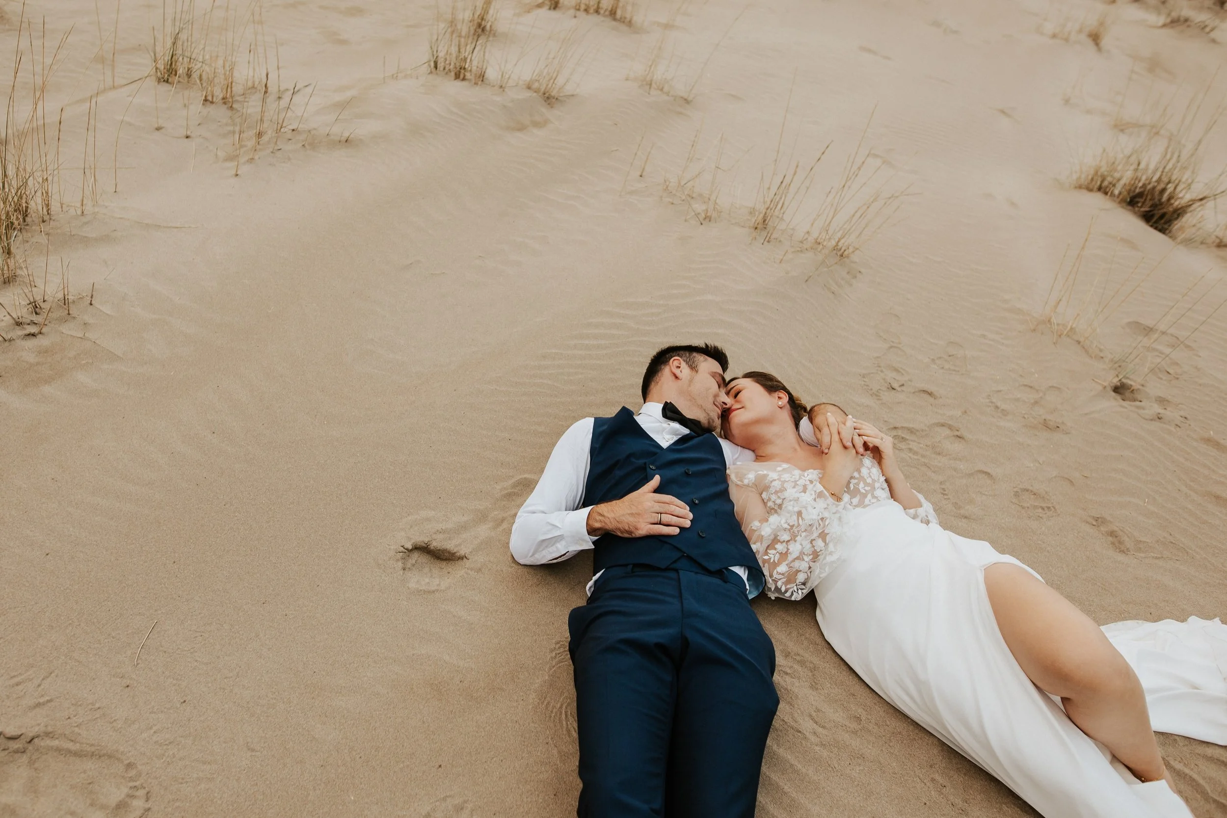 mariés couchés dans le sable de la plage