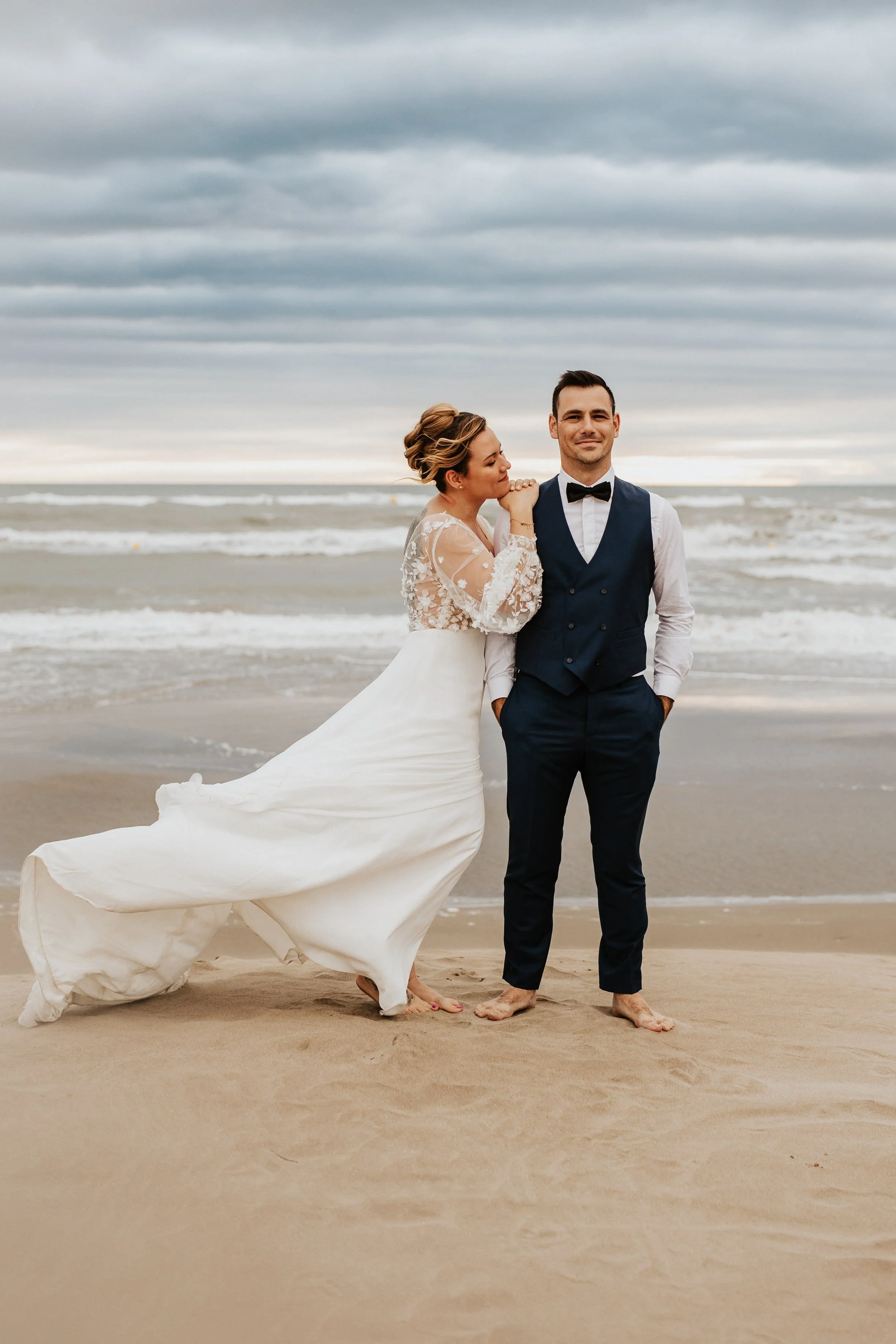 photo du couple les pieds dans l'eau en bord de mer avec la jolie lumière de fin de journée