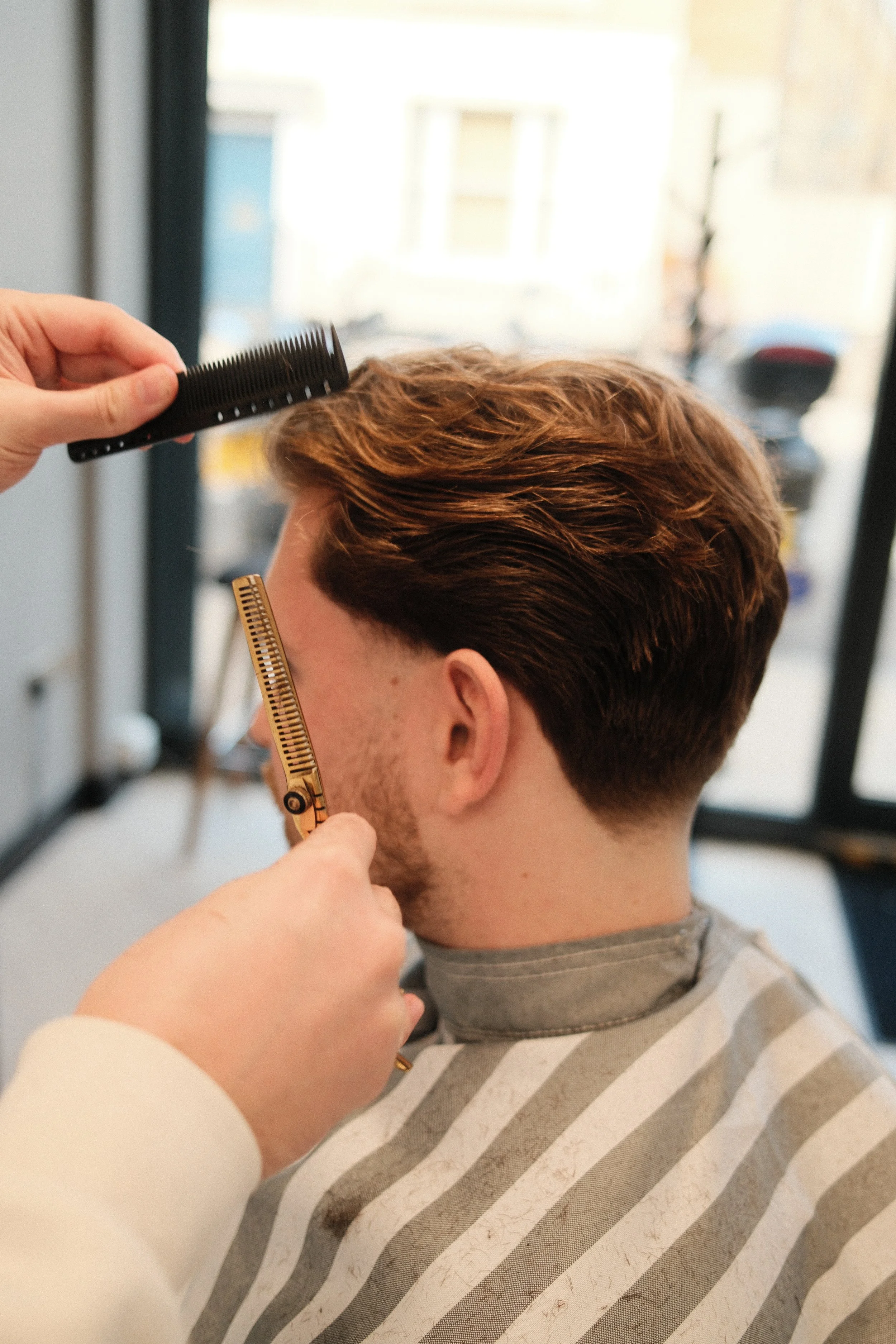 barber using scissors on a haircut. fulham barbers