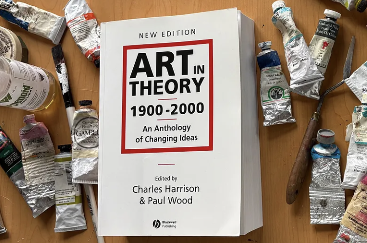 Art in Theory 1900–2000 on an artist’s worktable surrounded by paint tubes and art materials.