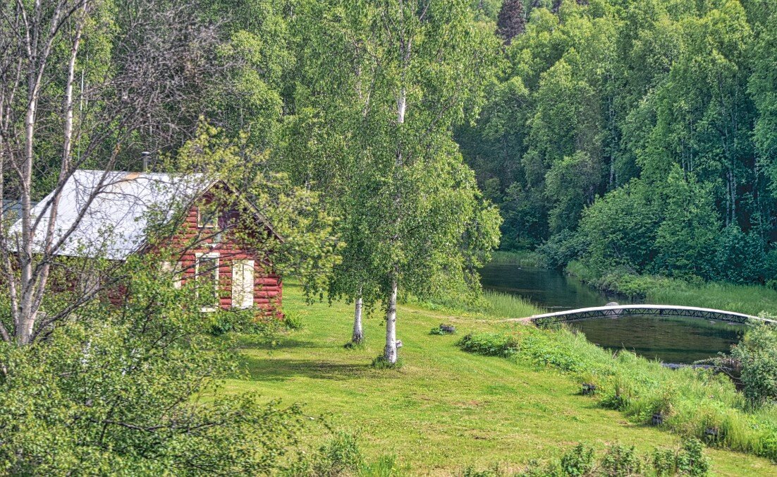 little-red-log-cabin-house-in-the-woods-next-to-a-river-with-a-foot-path-and-bridge-over-the-river_t20_xRagGg.jpg